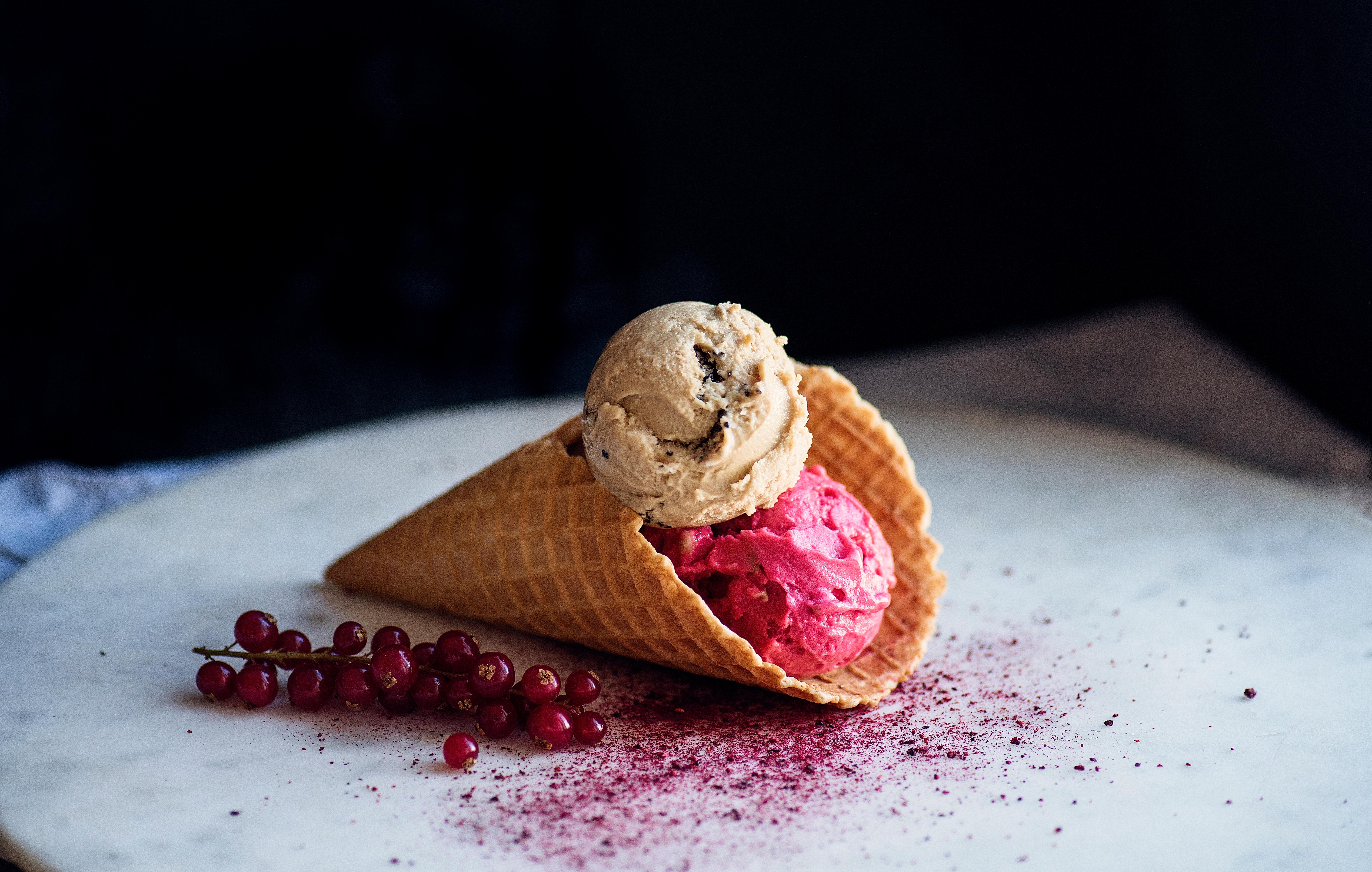 Ice-cream in a cone next to some red currants