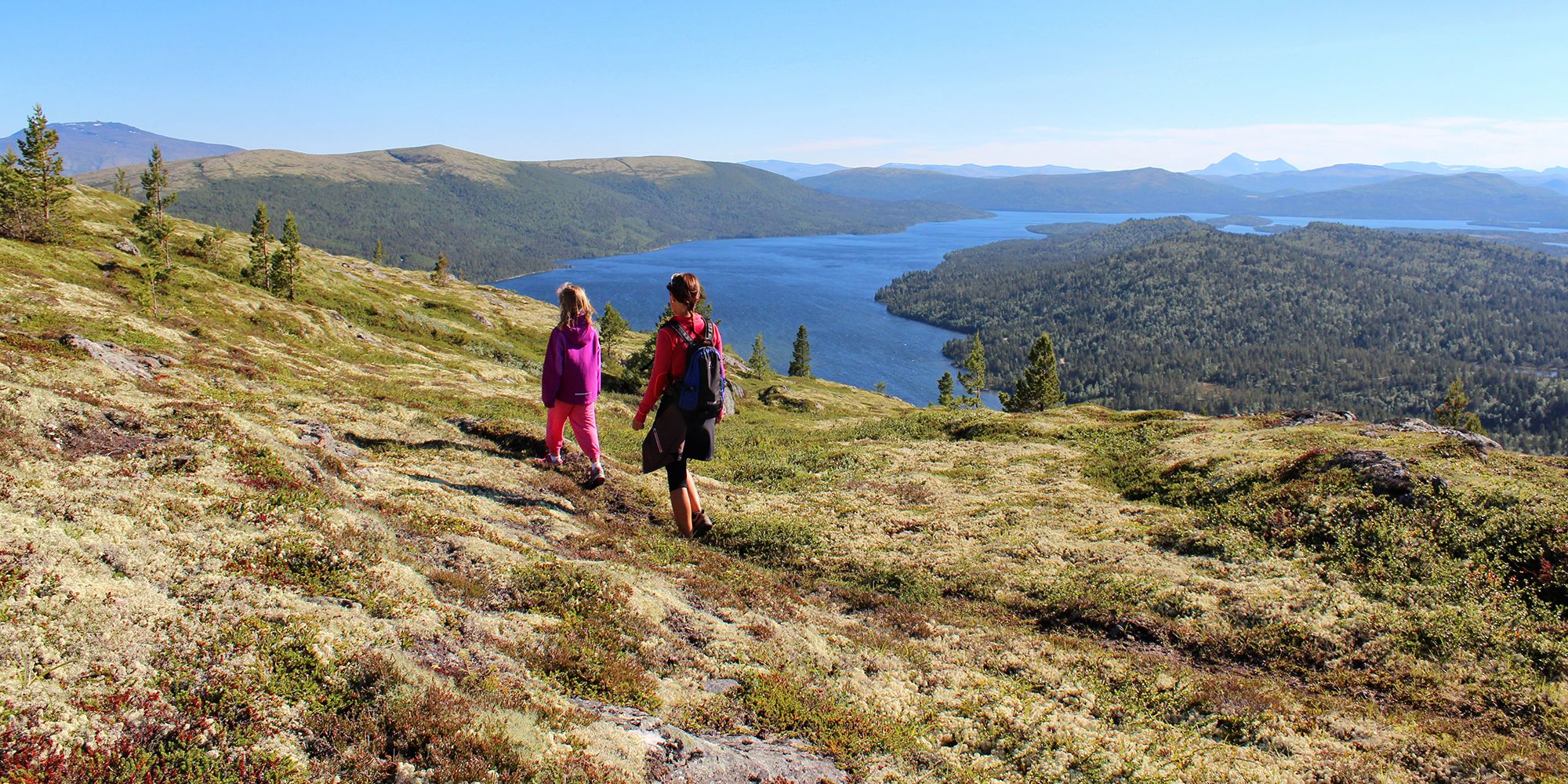 Two people hiking in the mountain terrain at Savalen