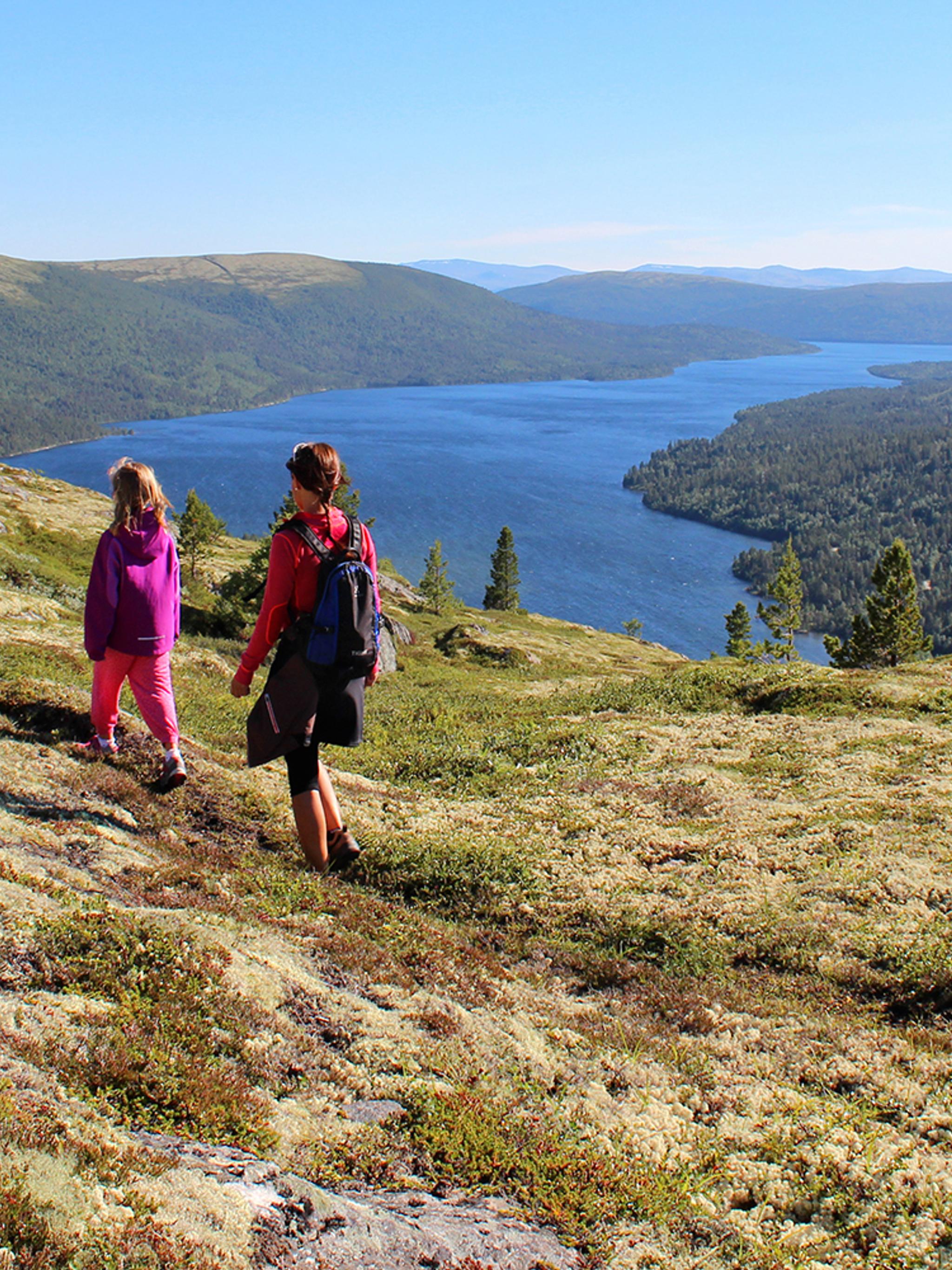 Two people hiking in the mountain terrain at Savalen