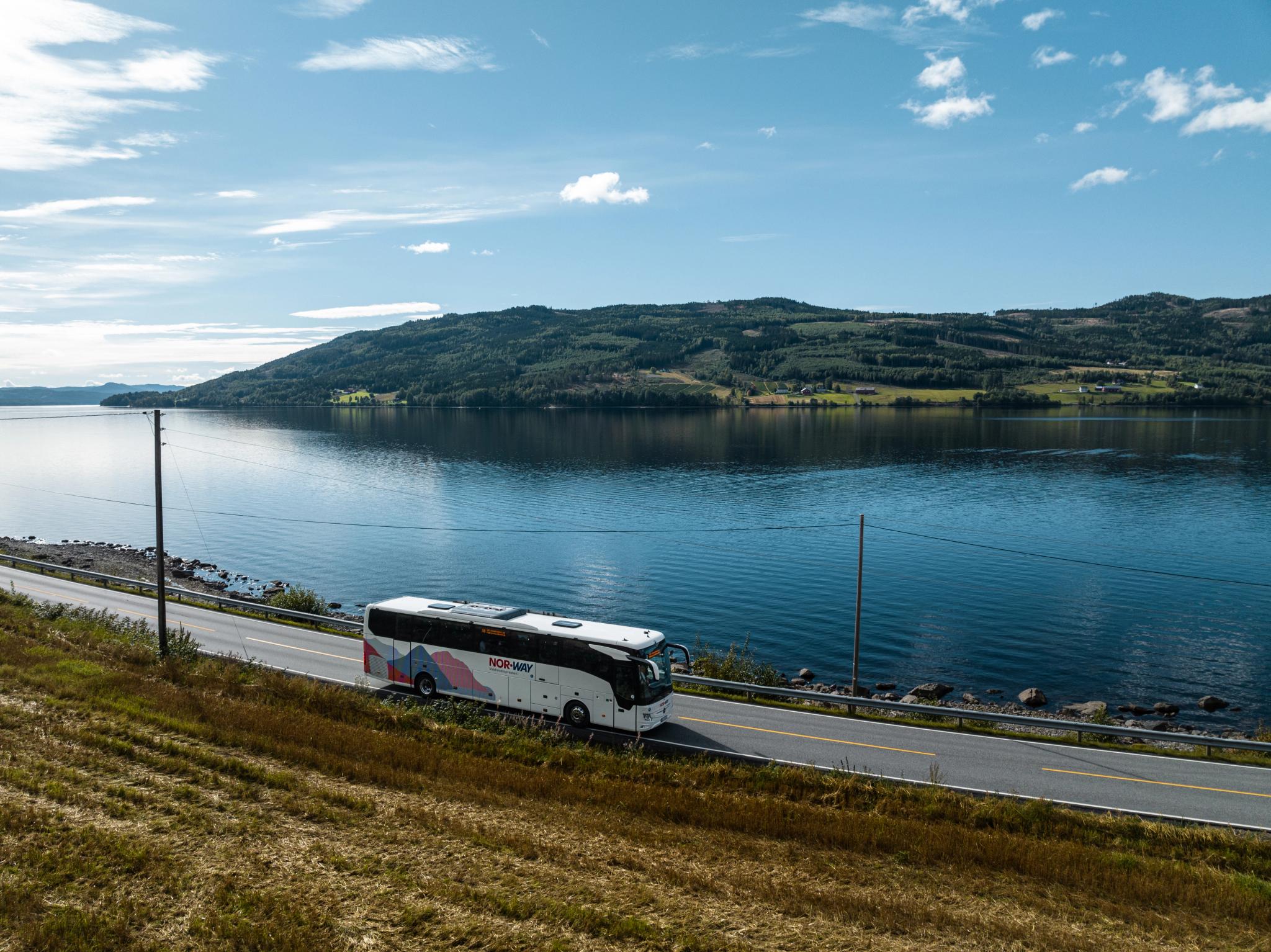 A bus from NOR-WAY Bussekspress driving along a fjord in Norway.