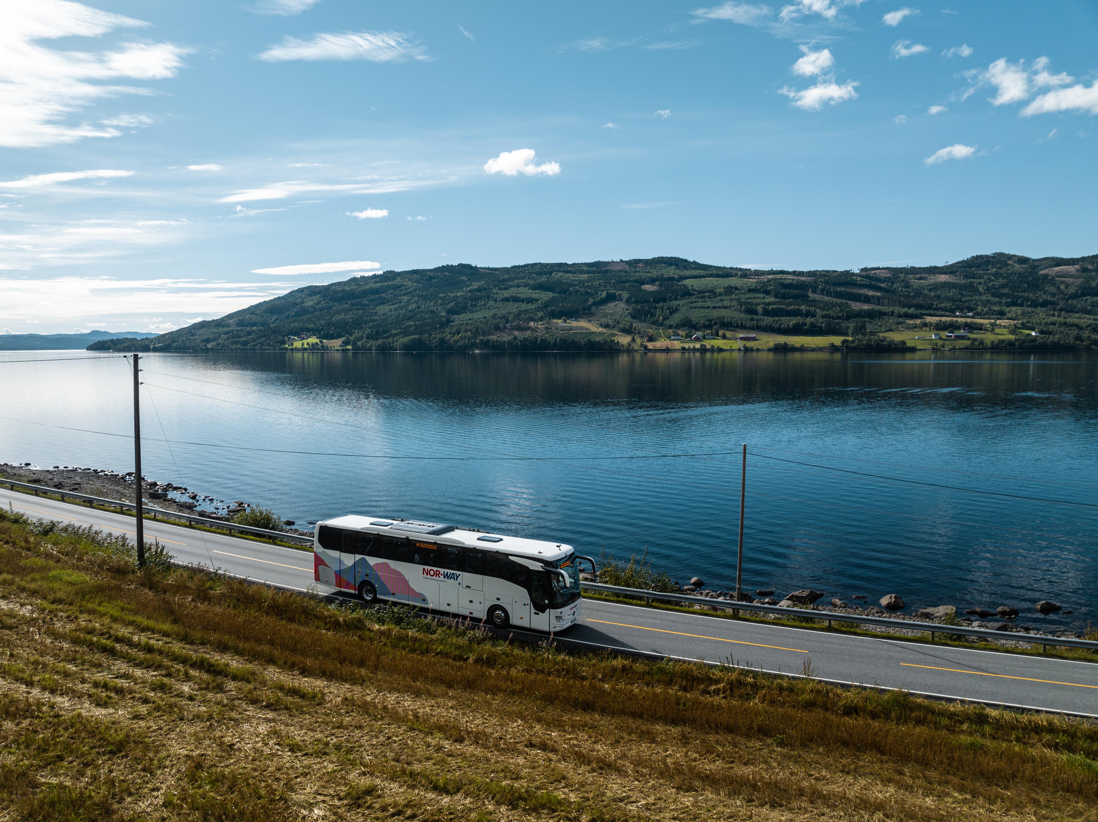 A bus from NOR-WAY Bussekspress driving along a fjord in Norway.