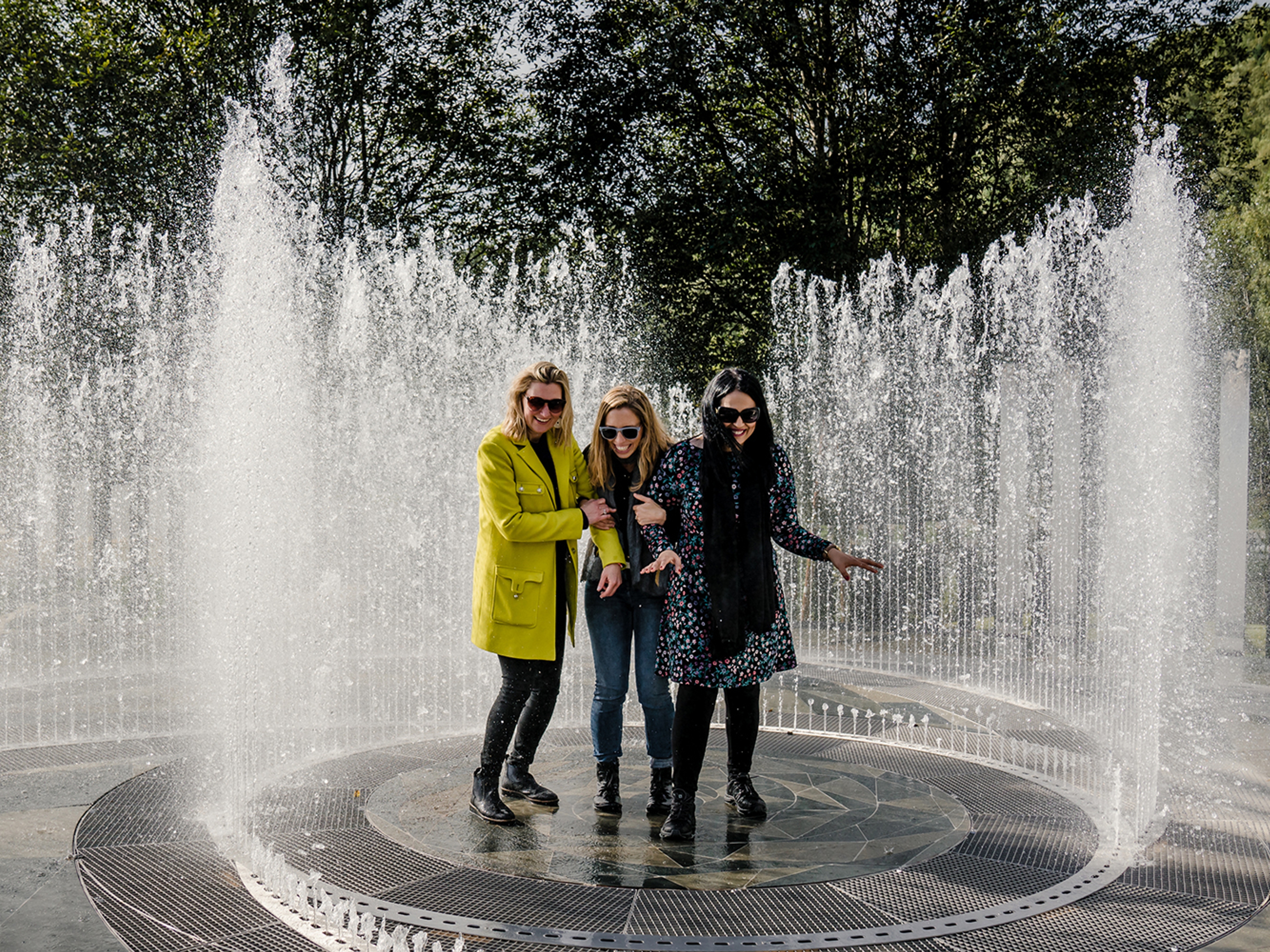 Four laughing women standing in the fountain surrounded by mirrors at Kistefos Museum in Hadeland