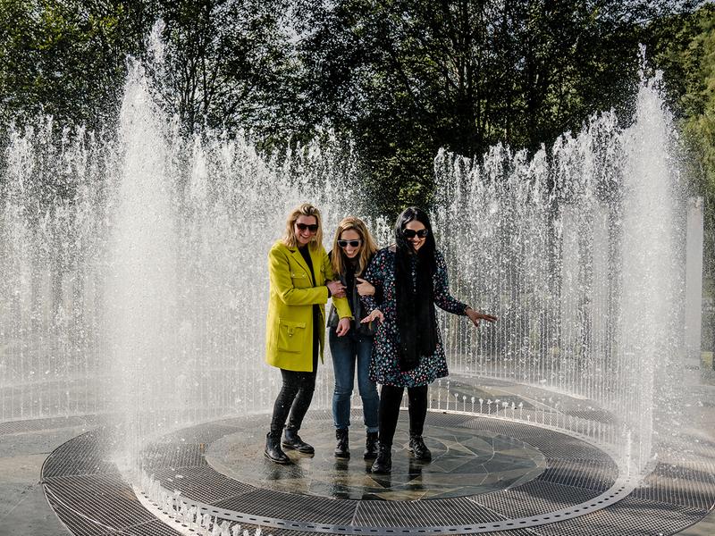 Four laughing women standing in the fountain surrounded by mirrors at Kistefos Museum in Hadeland