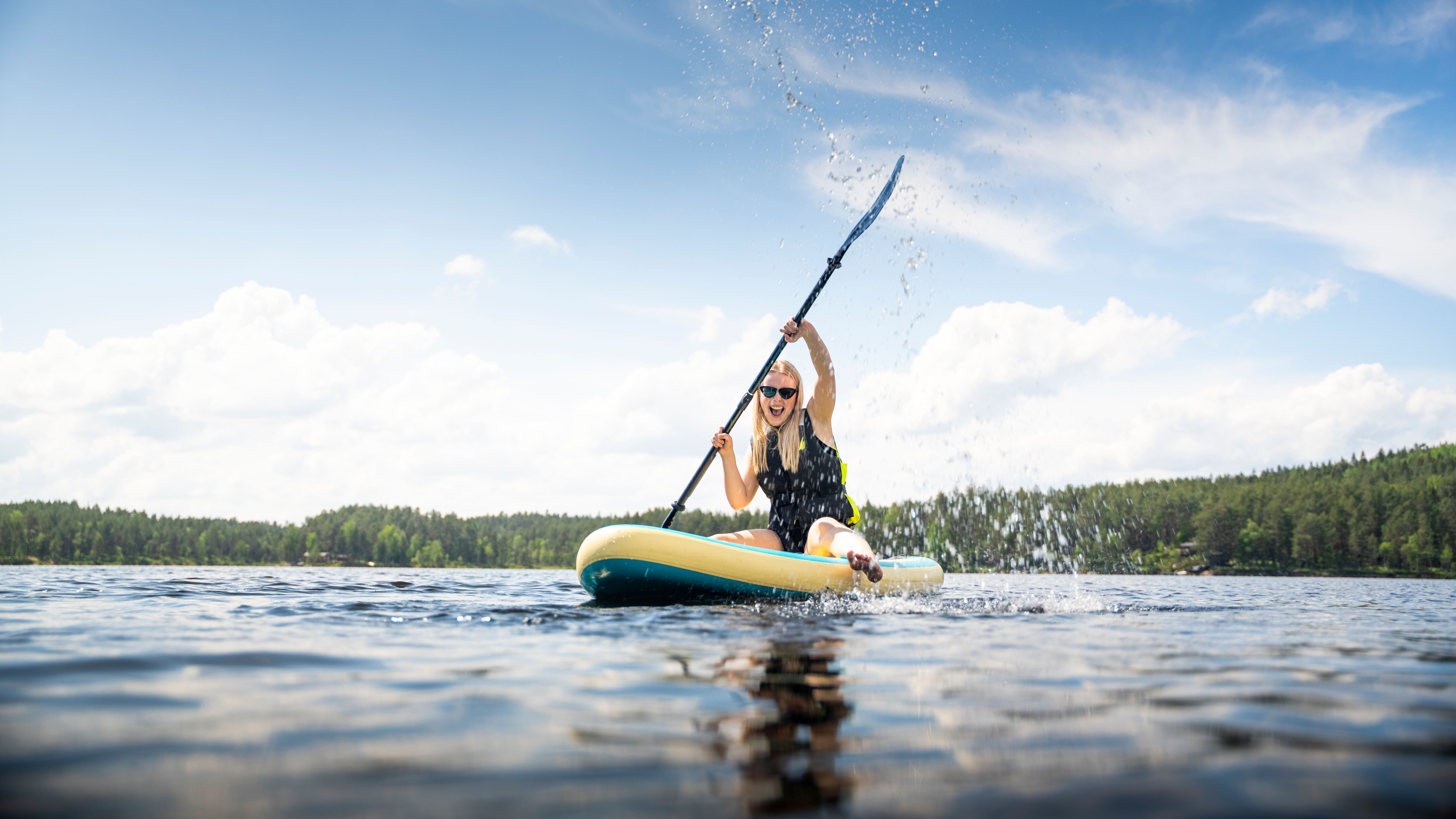 A girl rowing whilst sat on a paddle board