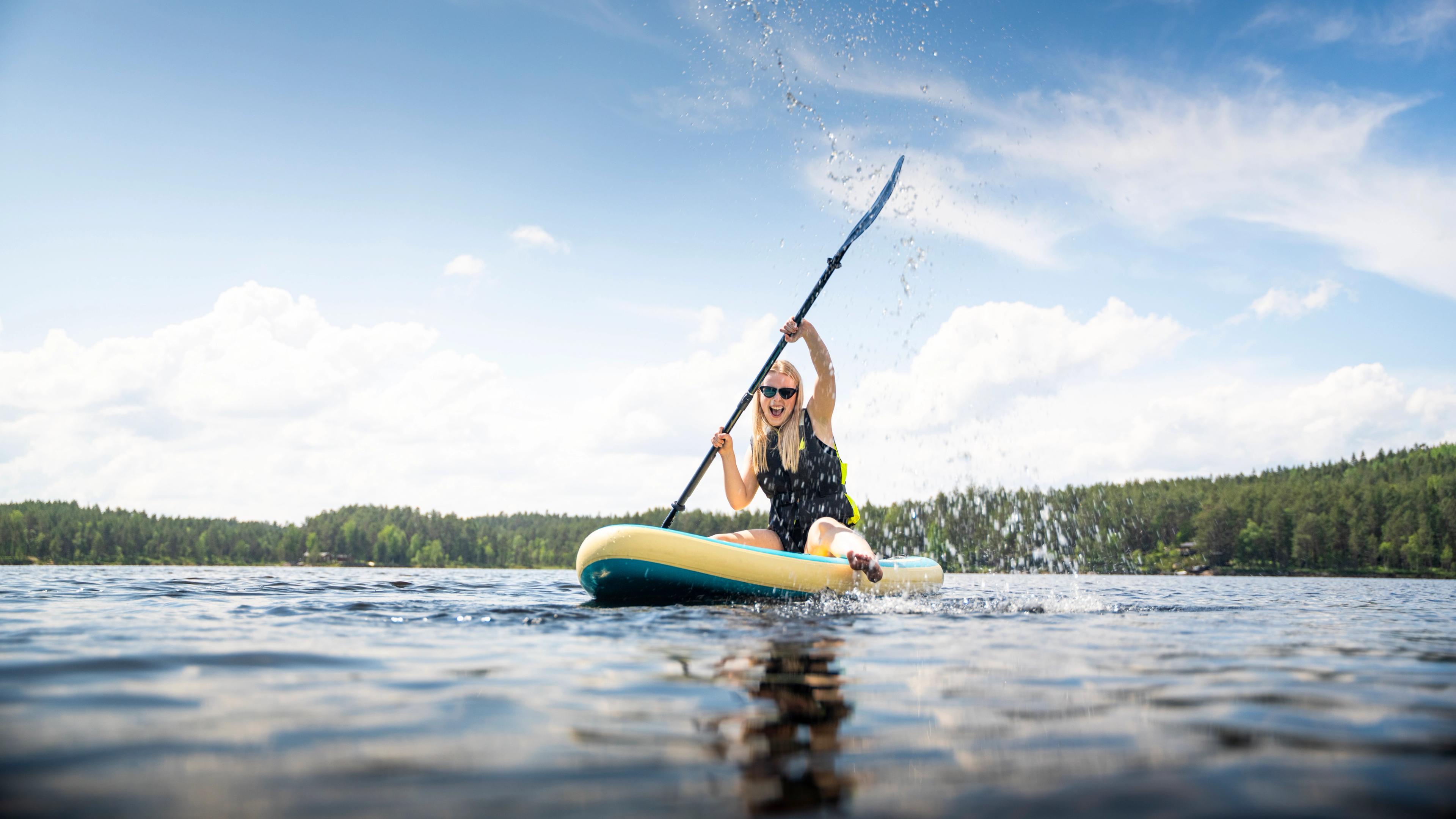 A girl rowing whilst sat on a paddle board