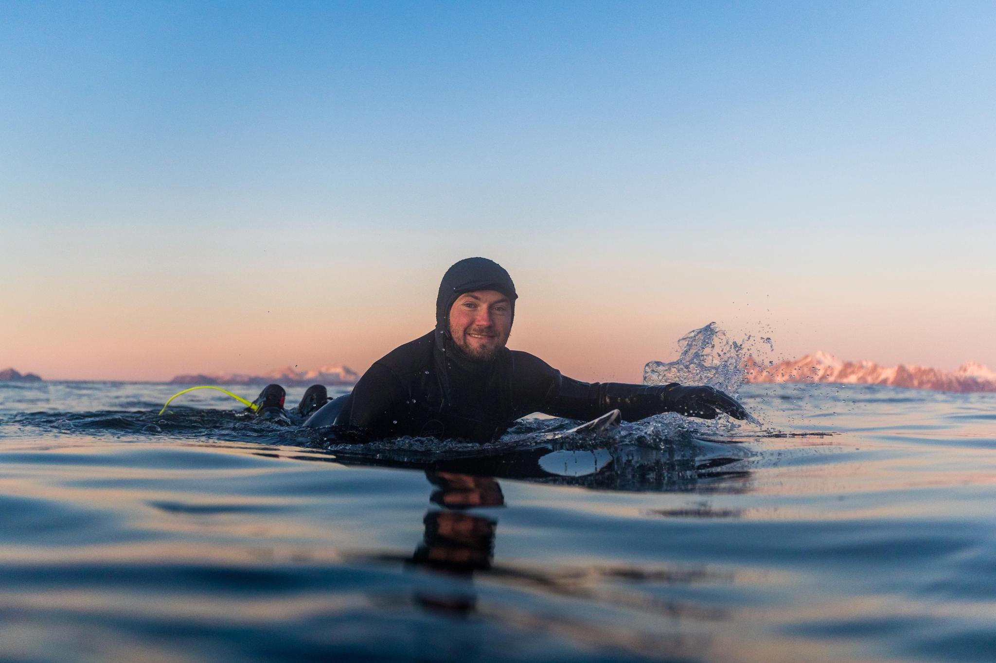 Close-up of a person lying on a surf board in the calm sea at Hoddevik in Fjord Norway