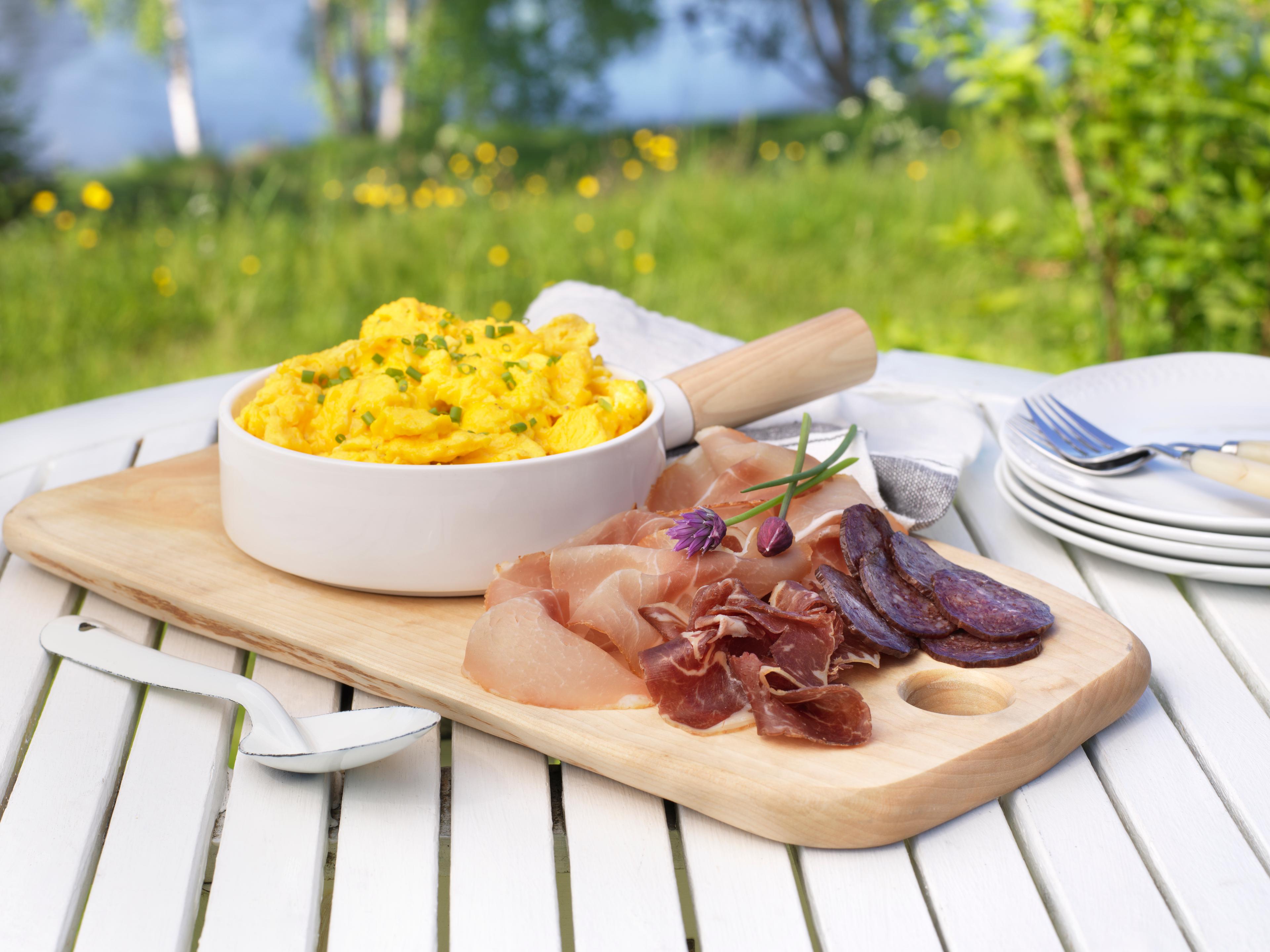 A serving of cured meat and a bowl of scrambled eggs in the garden.
