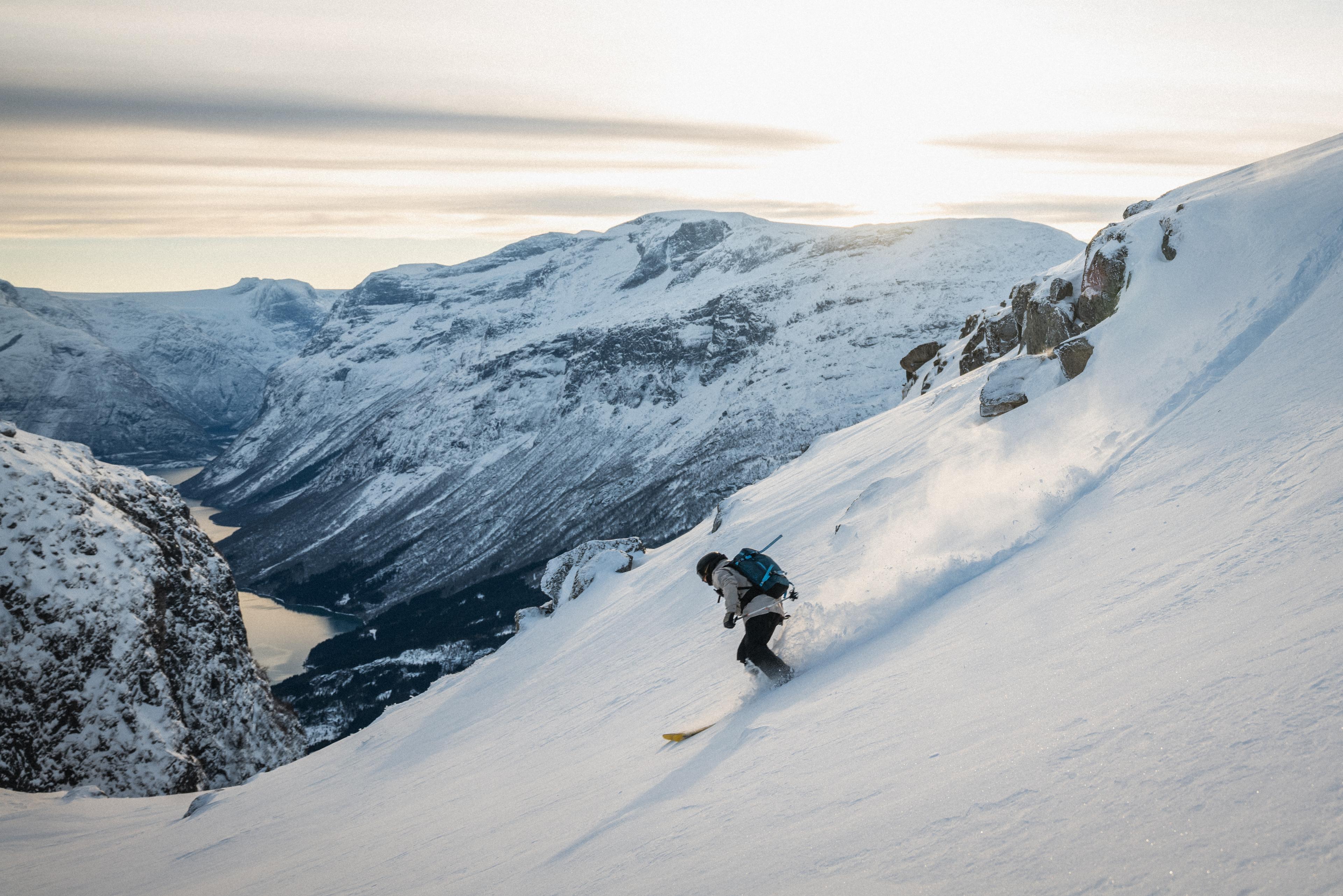 A person skiing down a mountain with a fjord view