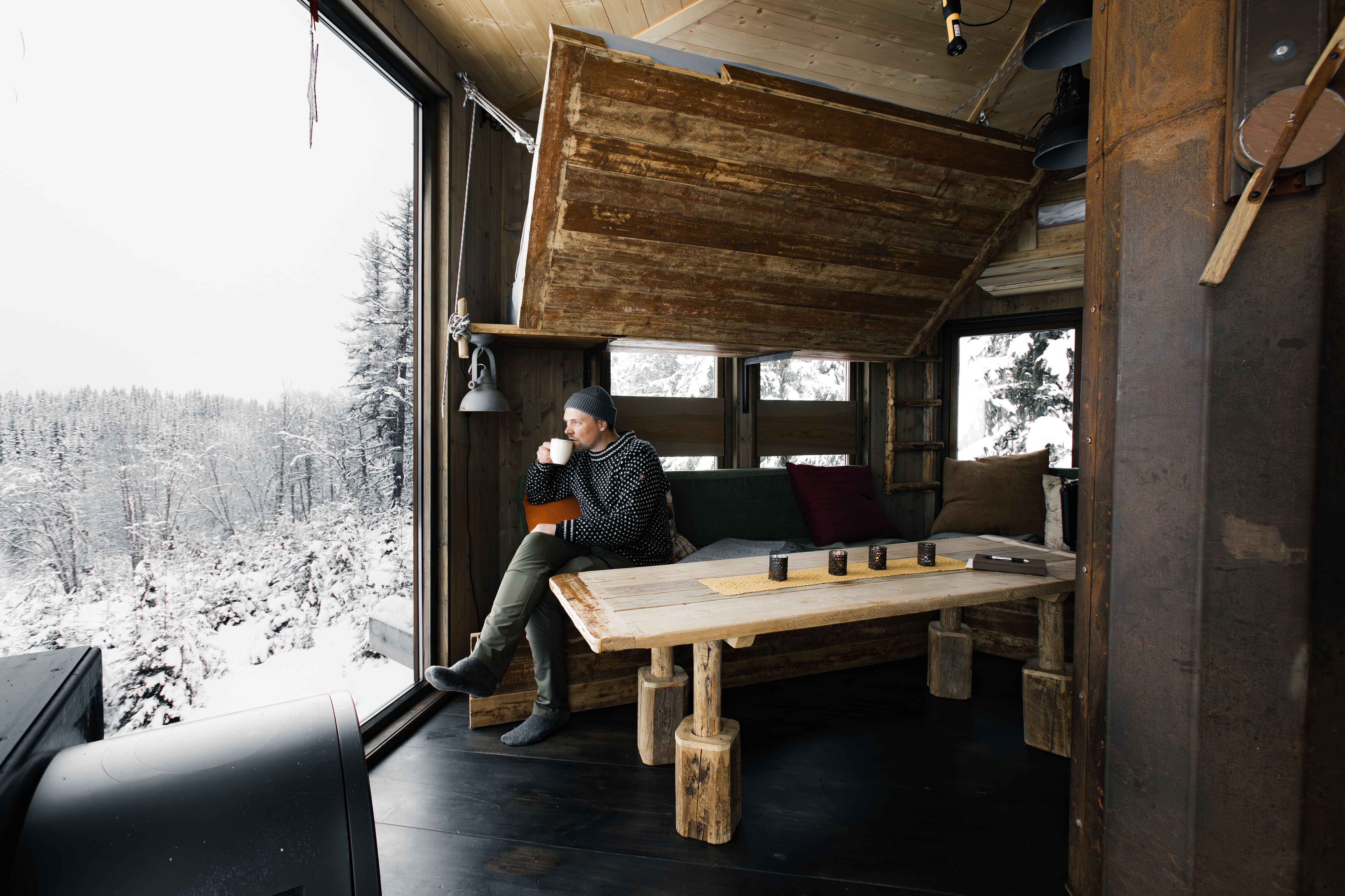 Man drinking coffee in a tree top hut.