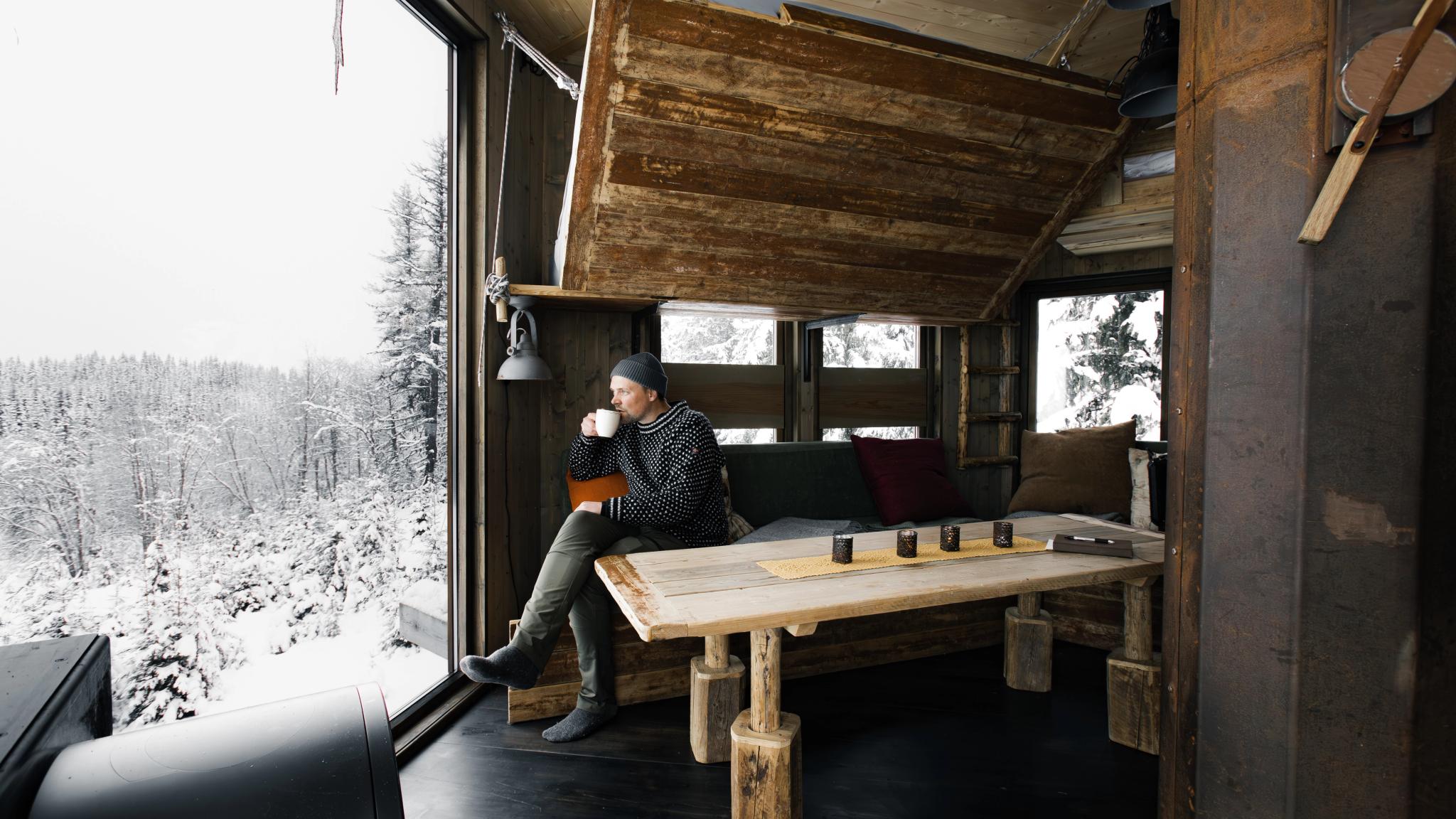 Man drinking coffee in a tree top hut.
