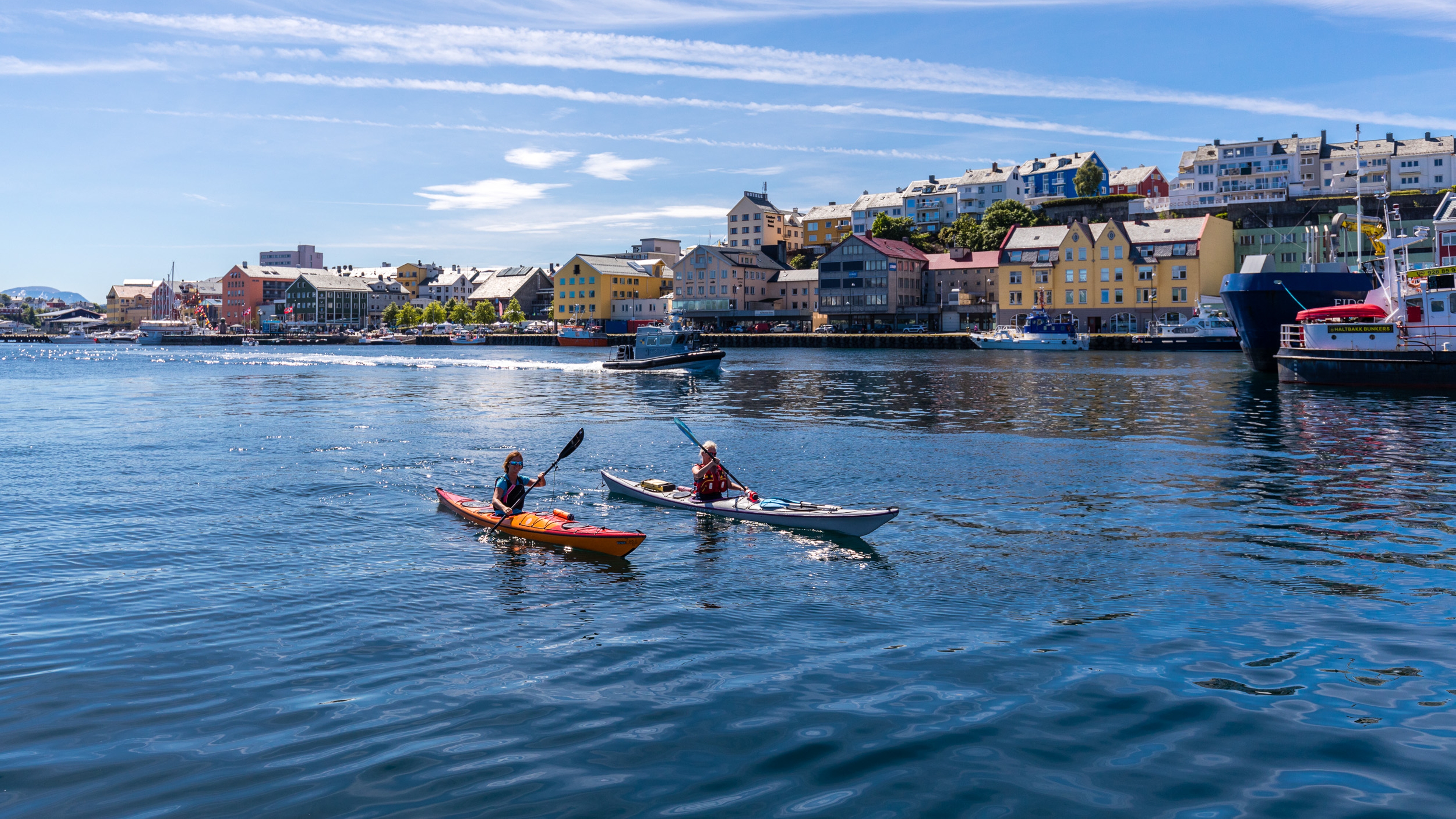 To personer padler kajakk i havna i Kristiansund på Vestlandet en solskinnsdag.