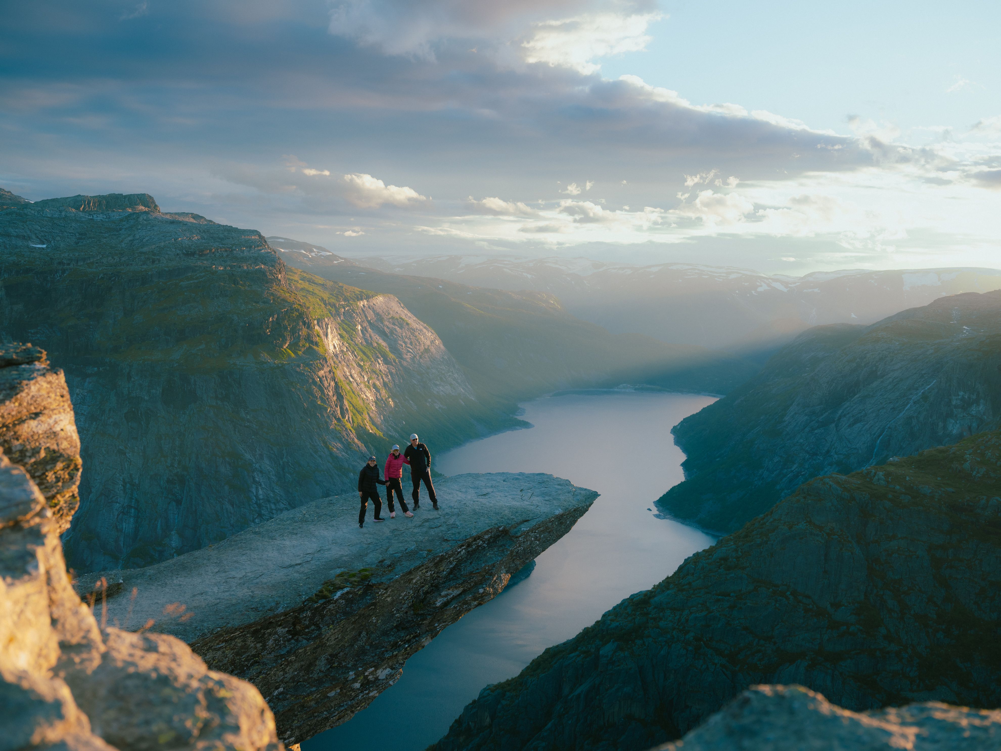 Three people on the mountain formation Trolltunga.