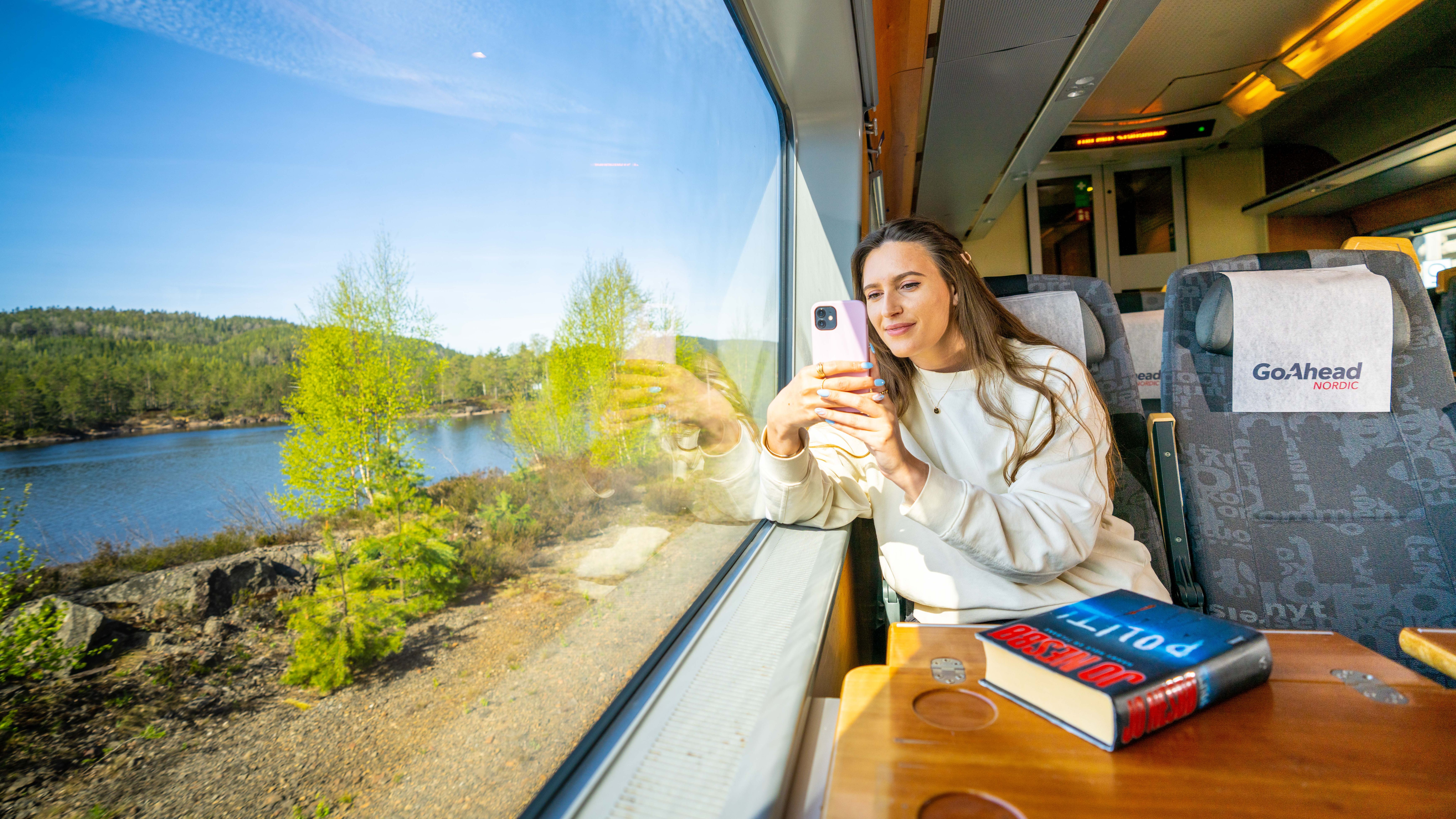 A woman takes a picture from the Sørland Line train from Oslo to Stavanger, Norway