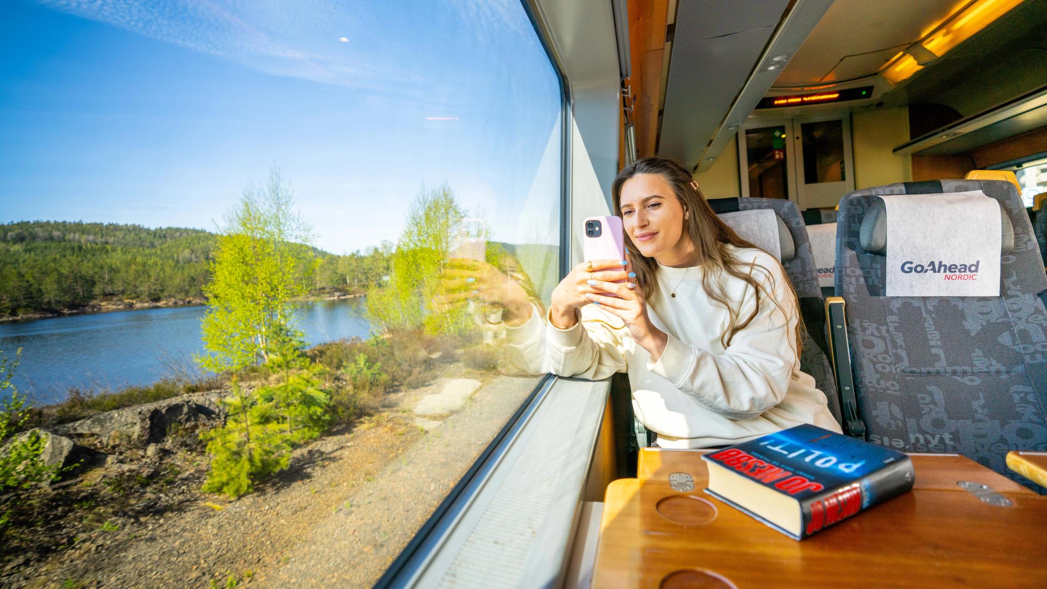 A woman takes a picture from the Sørland Line train from Oslo to Stavanger, Norway