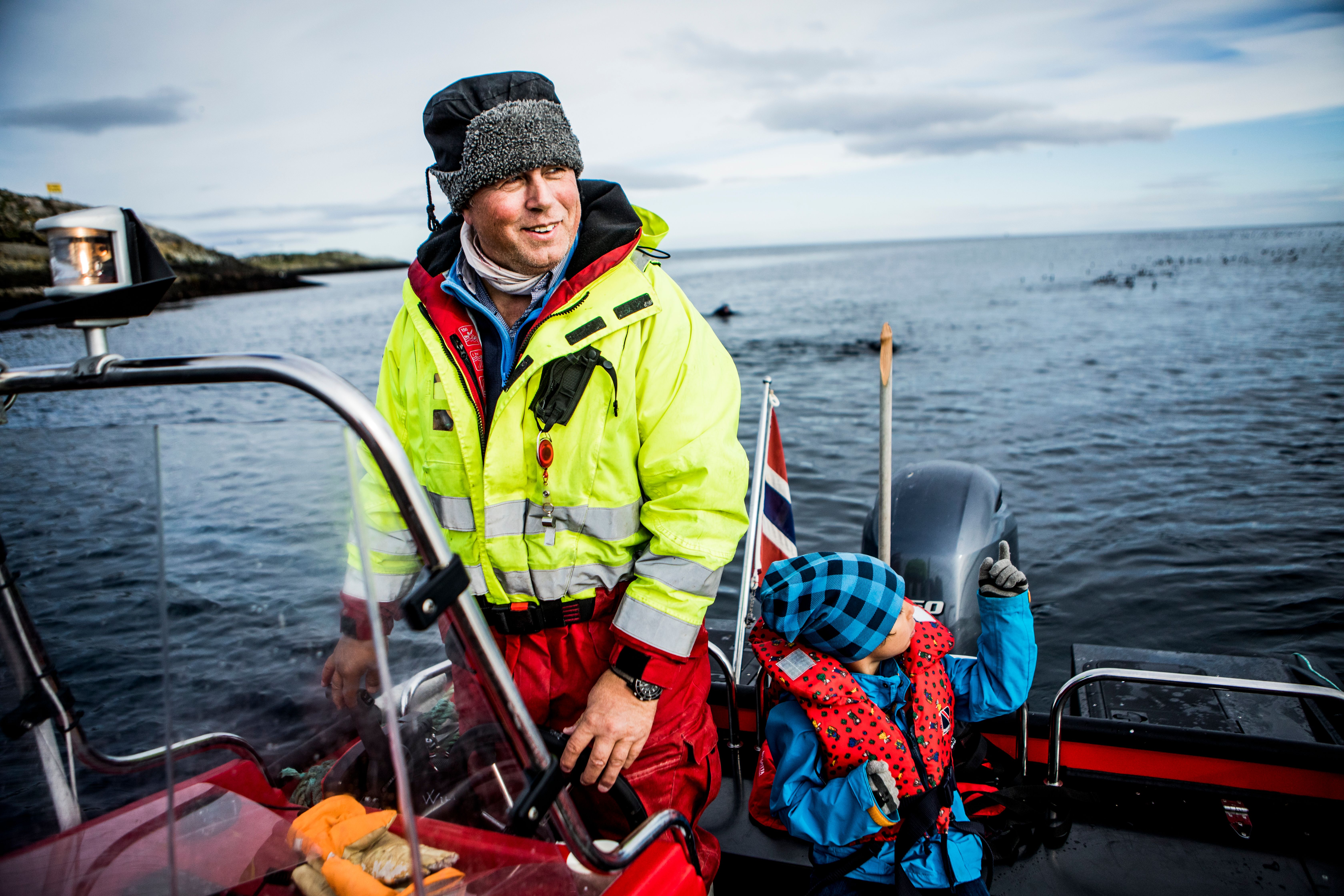Man and boy watching birds from a boat by Hornøya