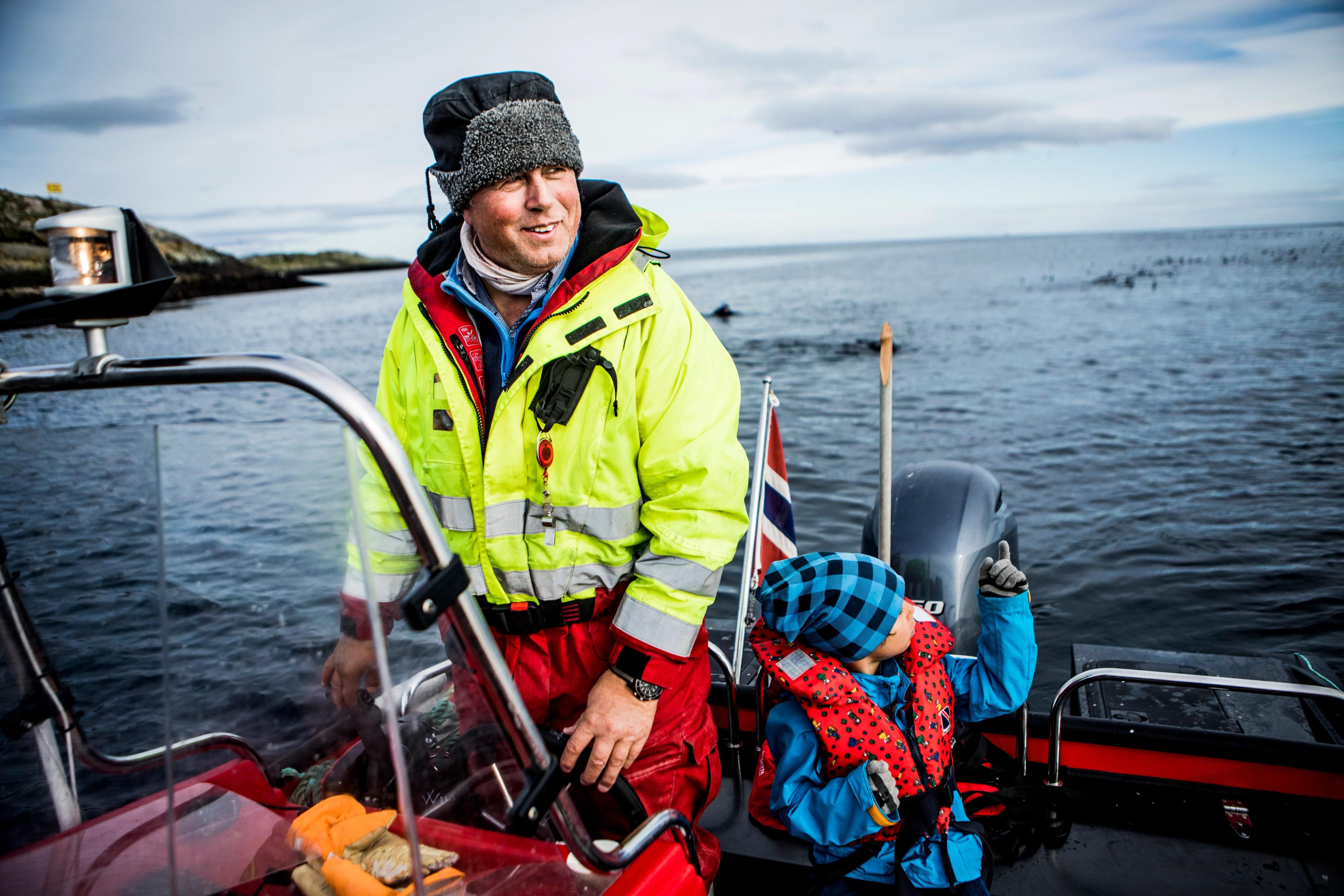 Man and boy watching birds from a boat by Hornøya
