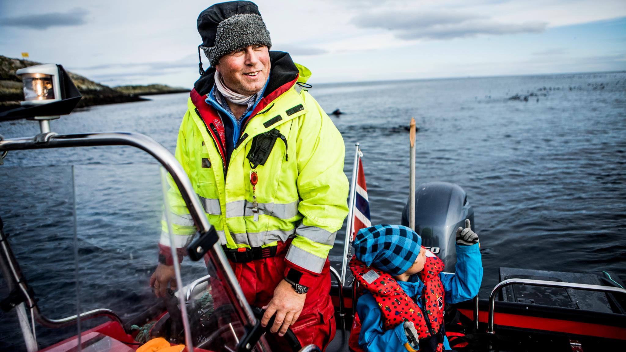 Man and boy watching birds from a boat by Hornøya