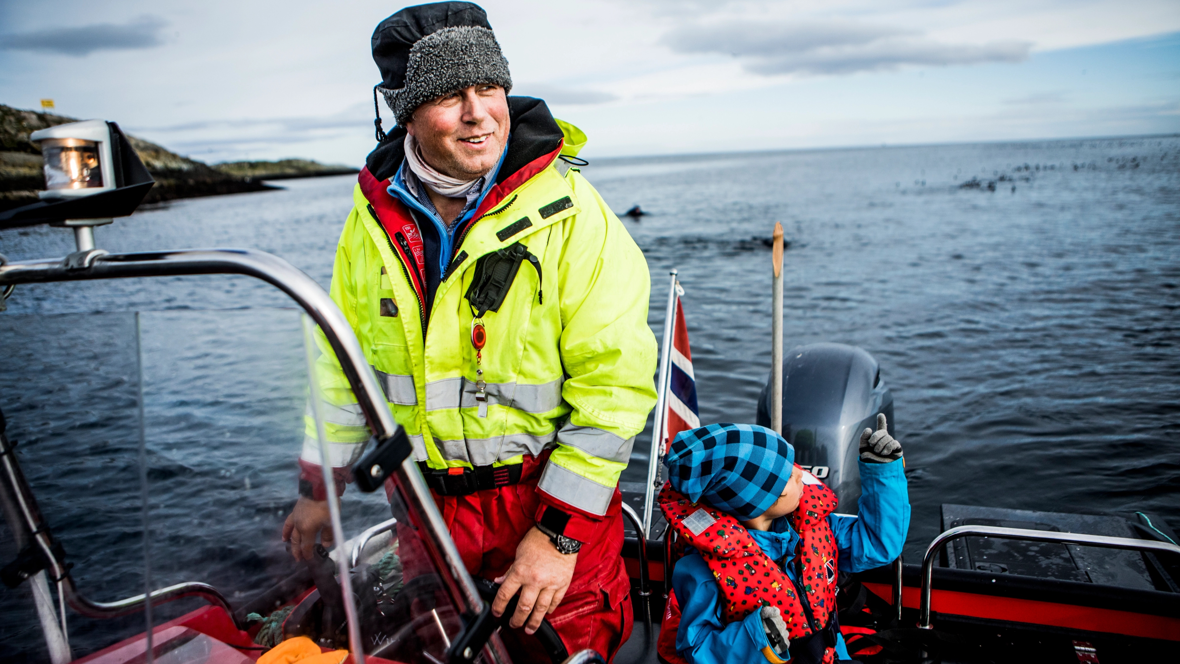 Man and boy watching birds from a boat by Hornøya