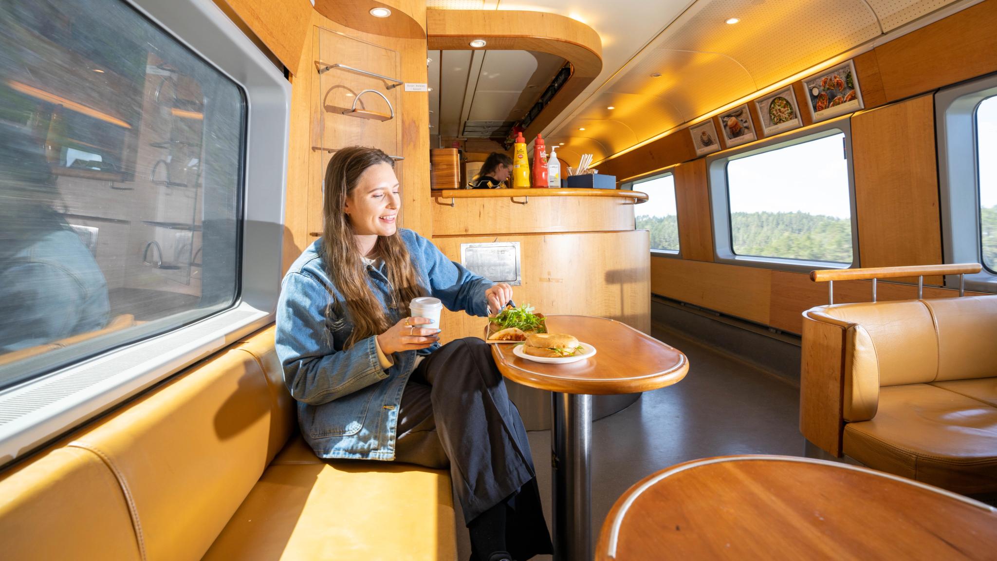 A woman eating food at the Sørland Railway train
