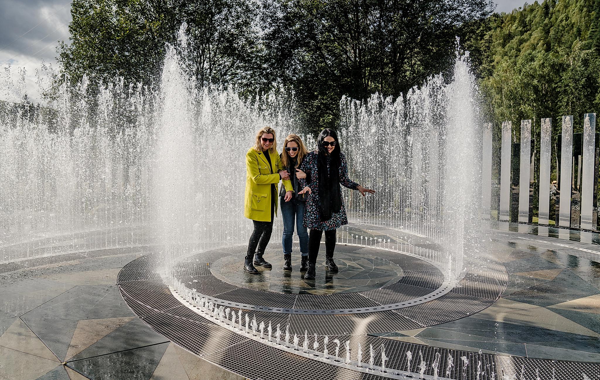 Vier Frauen stehen im Brunnen, umrundet von Spiegeln im Kistefoss Museum in Norwegen