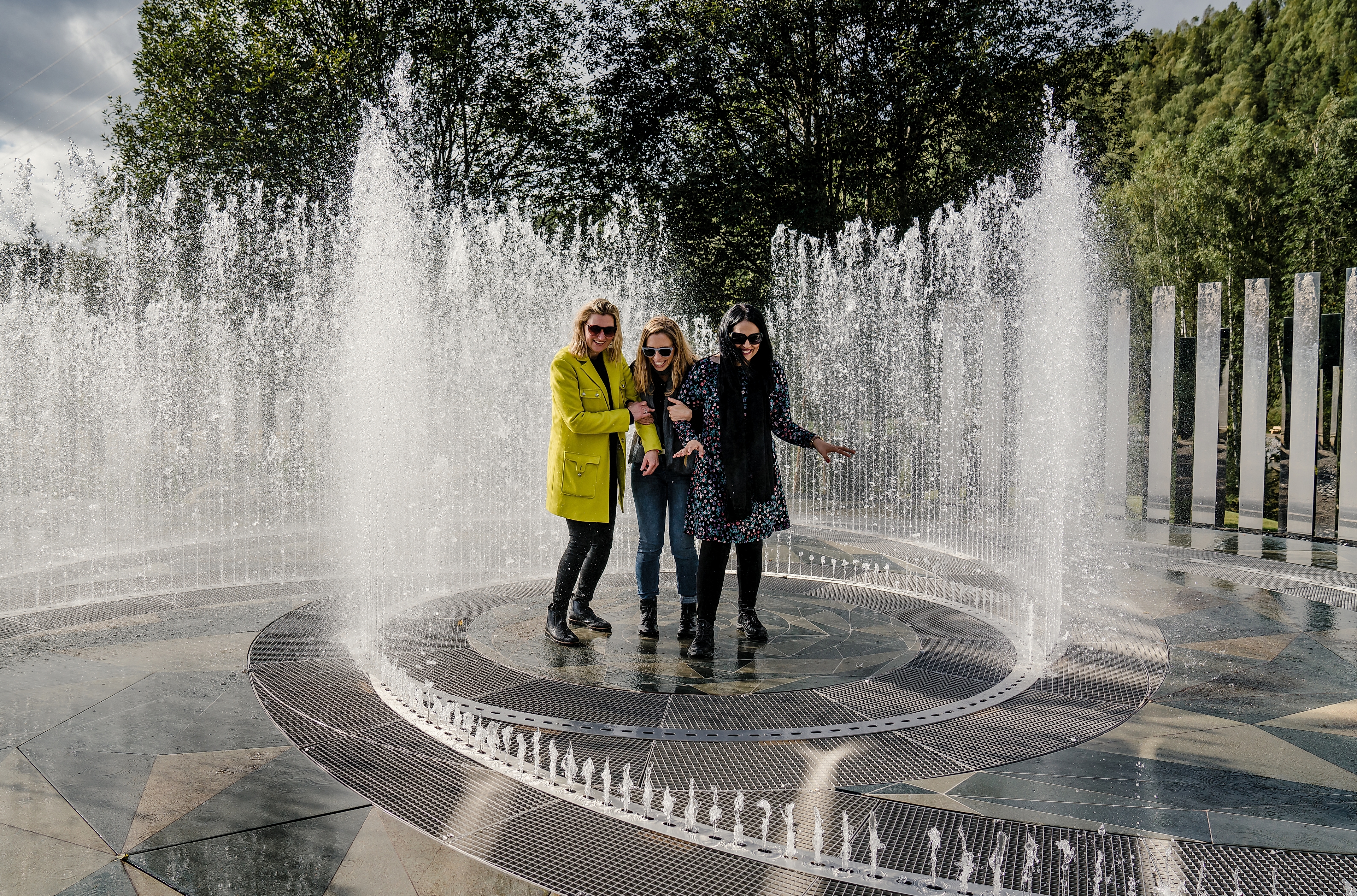Four laughing women standing in the fountain surrounded by mirrors at Kistefos Museum in Hadeland