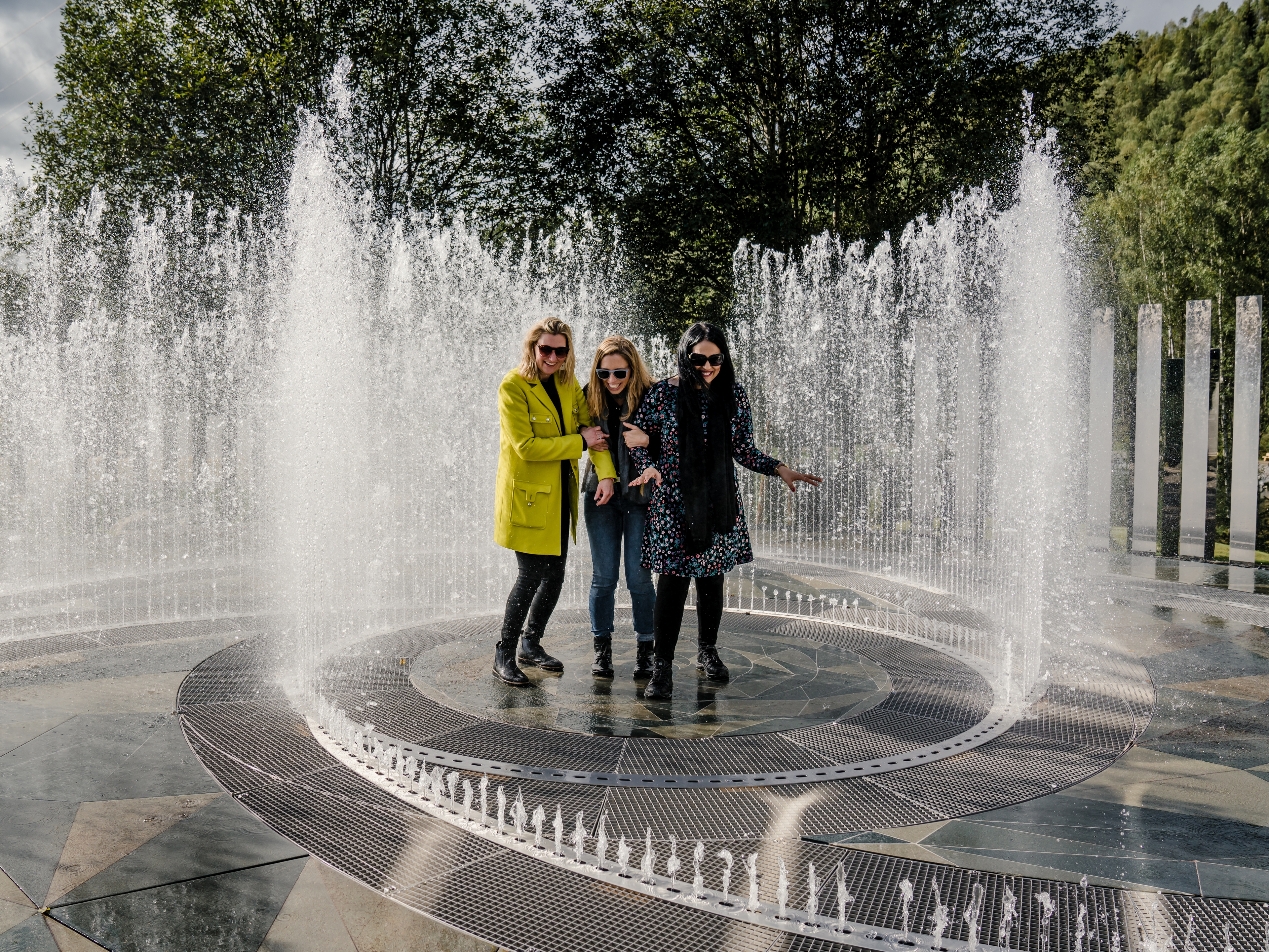 Four laughing women standing in the fountain surrounded by mirrors at Kistefos Museum in Hadeland