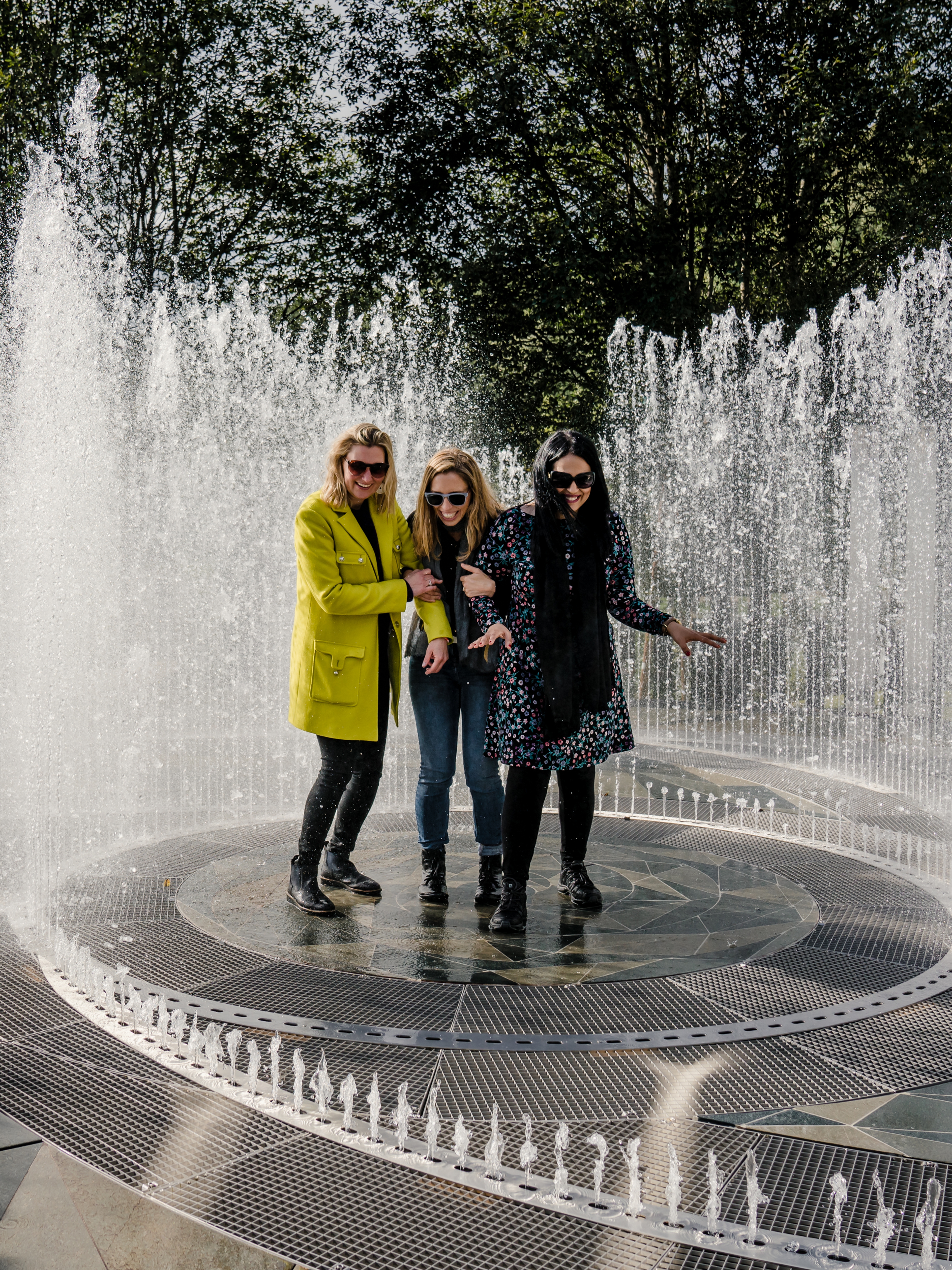 Four laughing women standing in the fountain surrounded by mirrors at Kistefos Museum in Hadeland