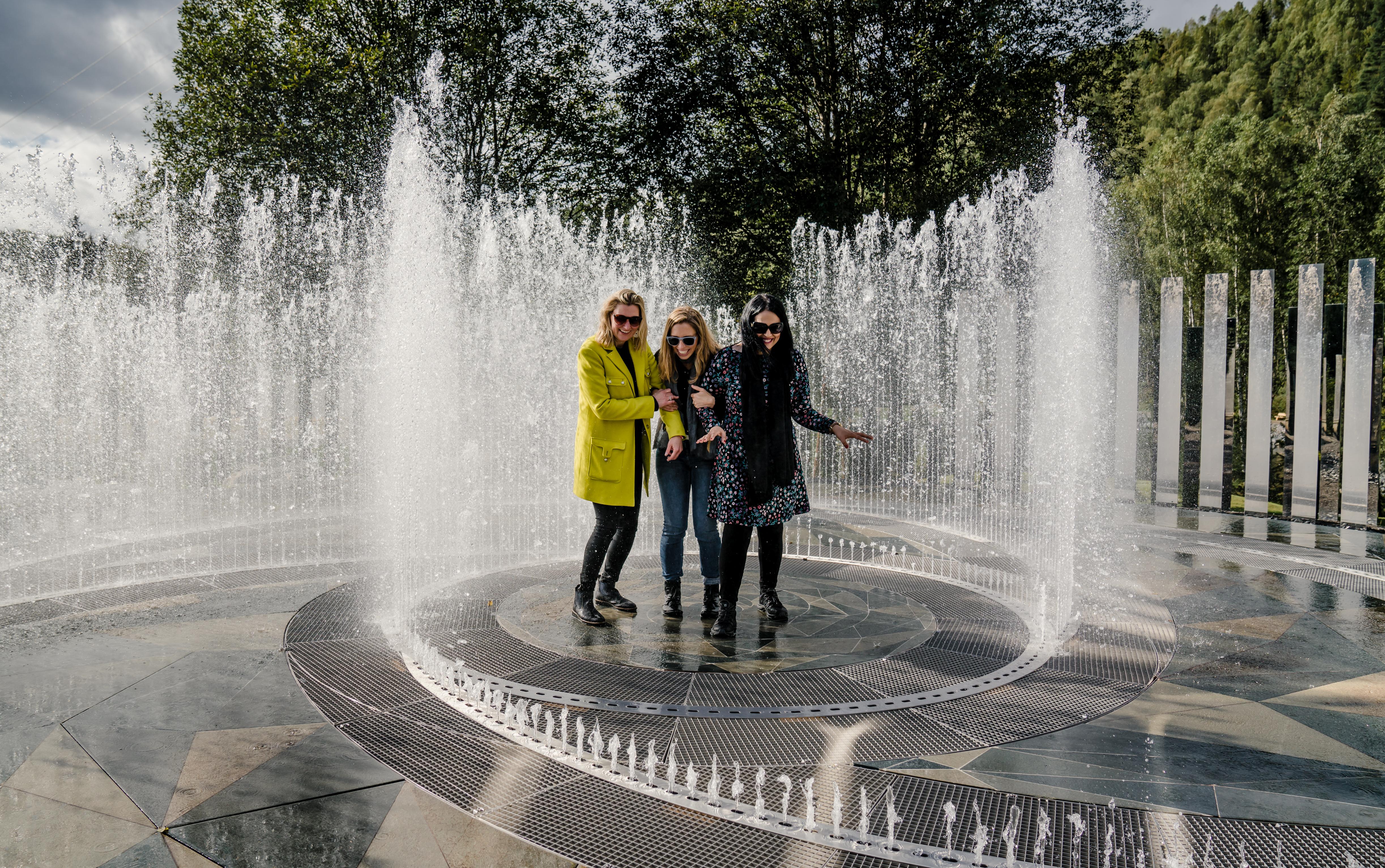 Fyra skrattande kvinnor står i fontänen som omges av speglar på Kistefos Museum i Hadeland