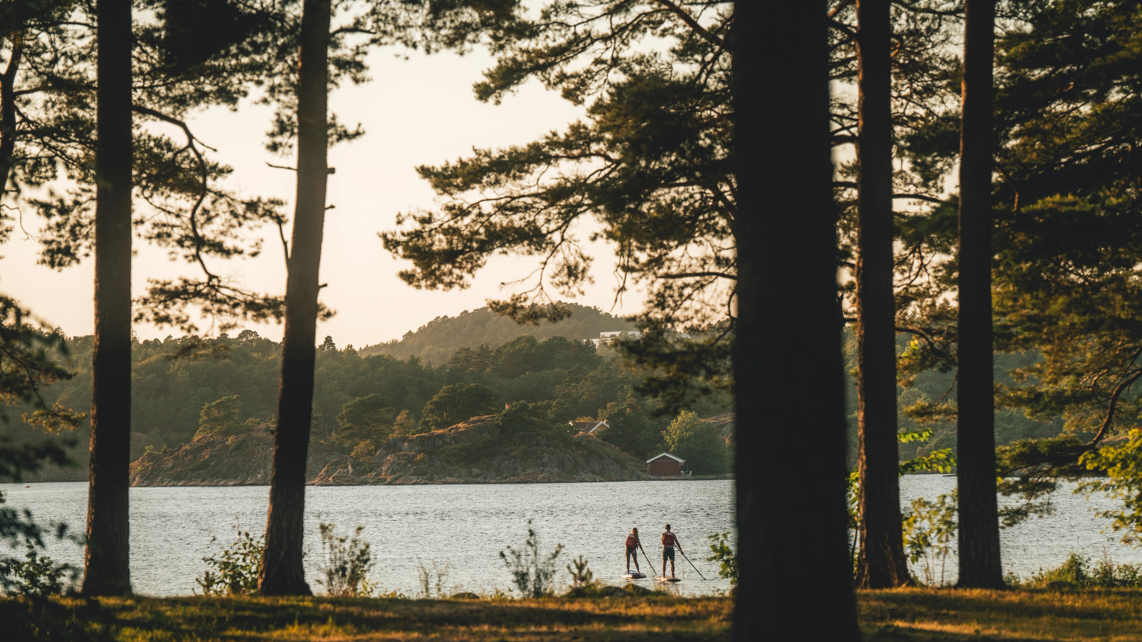 A couple paddle boarding at Raet camping, Arendal