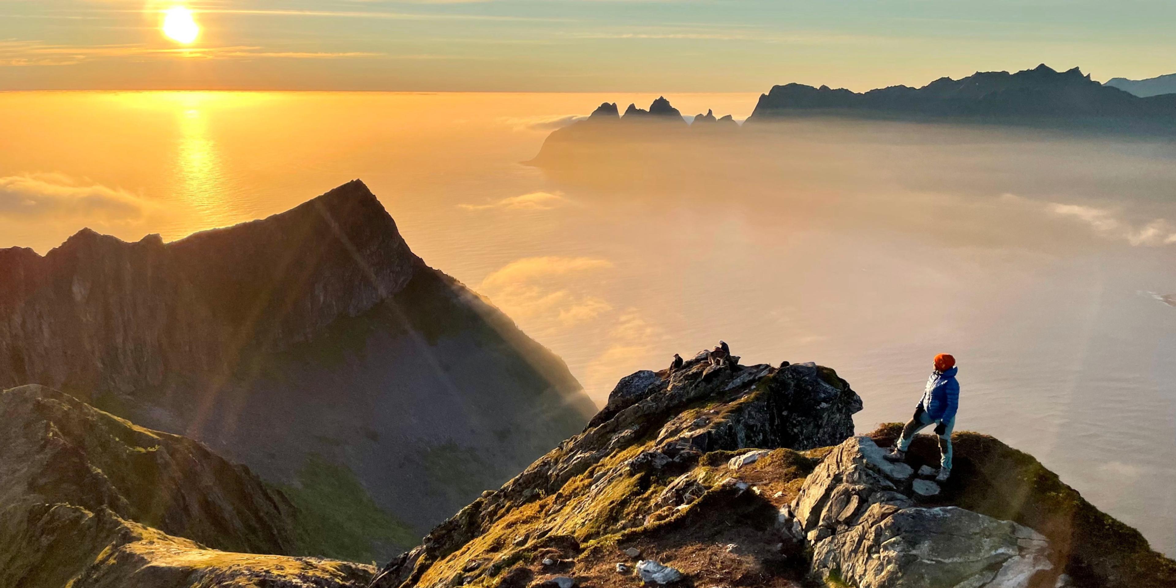 A woman standing at the peak of Husfjellet in Senja
