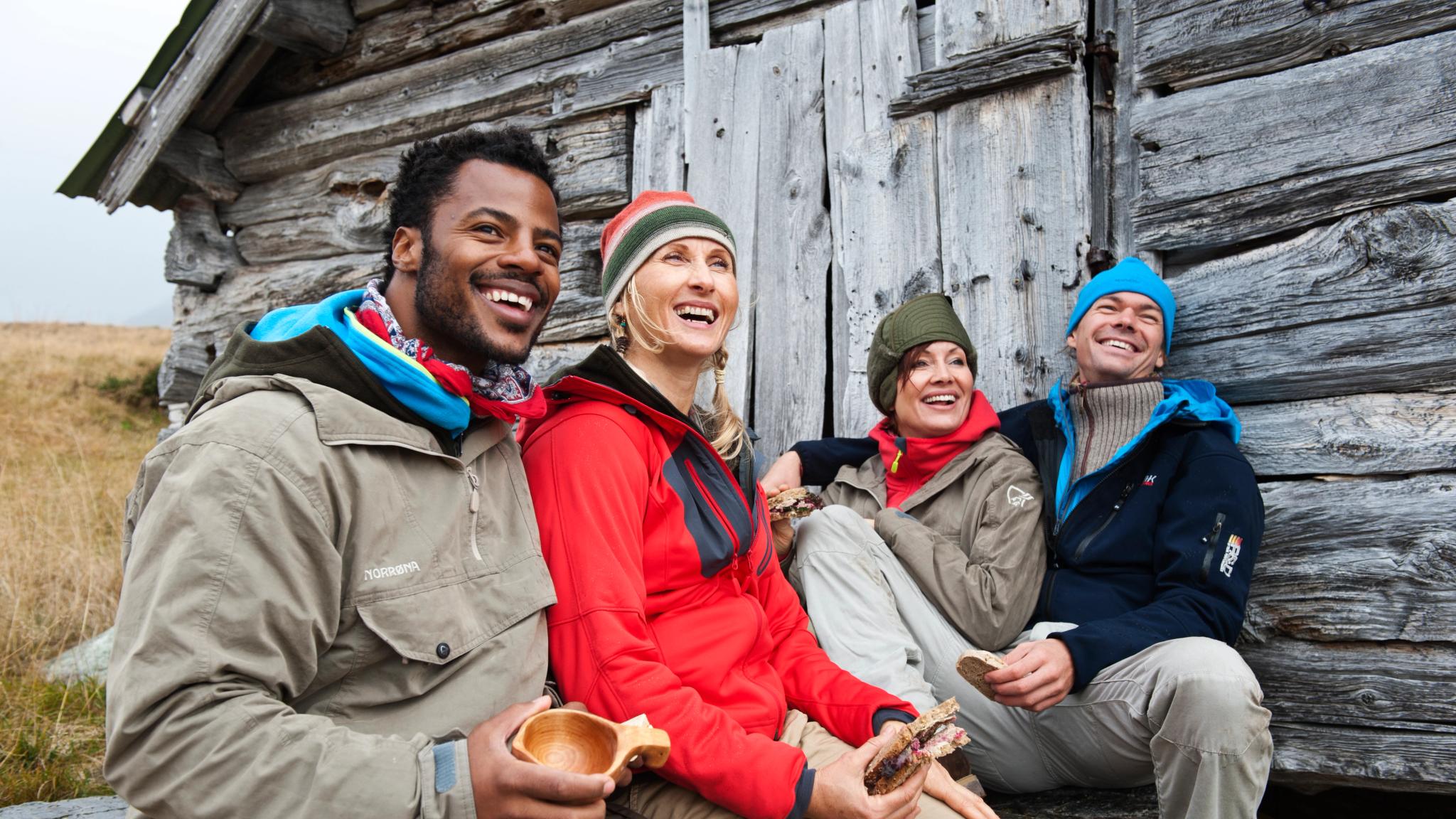 Four happy people sitting outside of a mountain cabin in Beitostølen, Eastern Norway