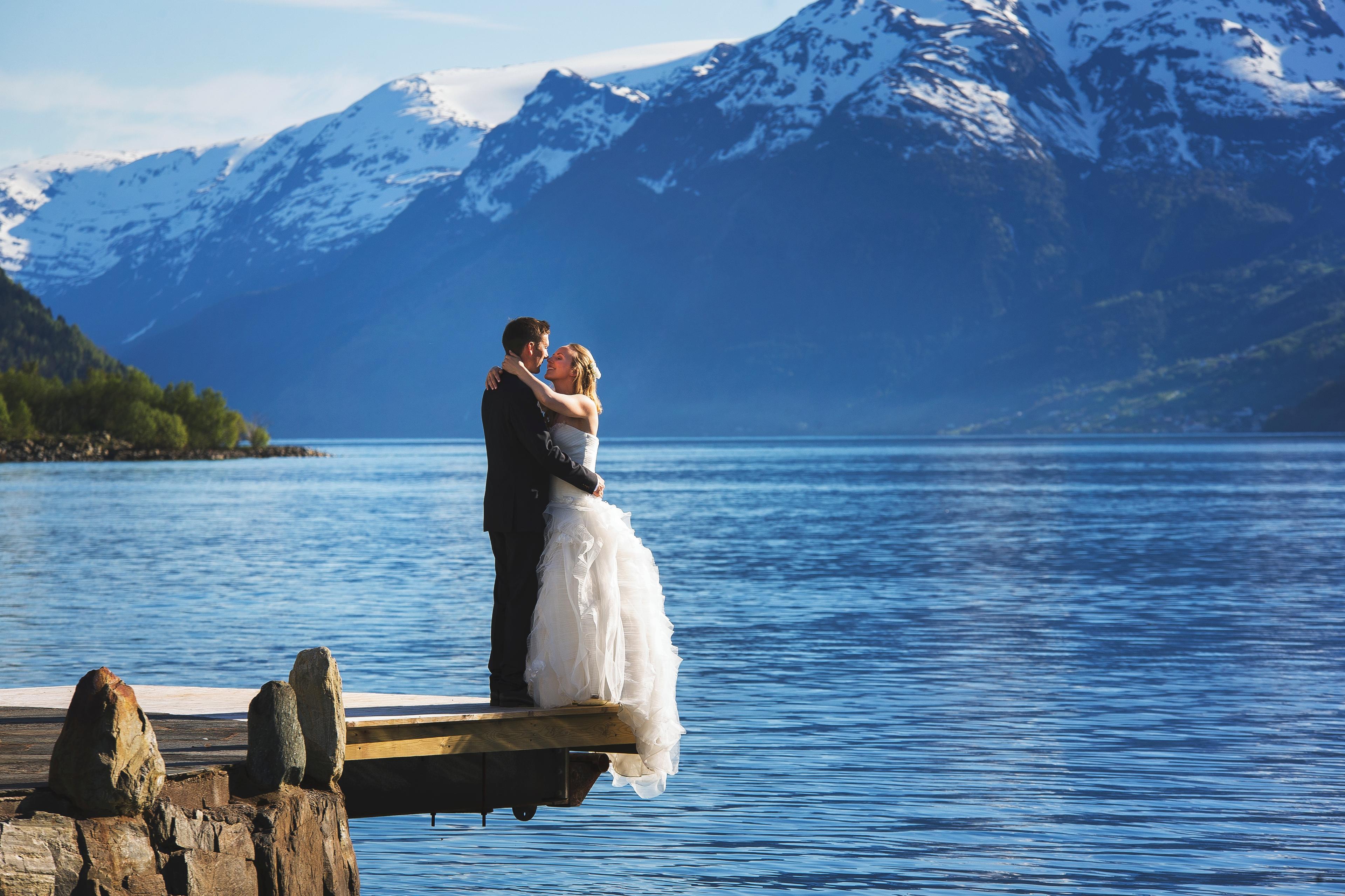 A bride and groom out by the fjord with mountains in the background in Ullensvang in Fjord Norway