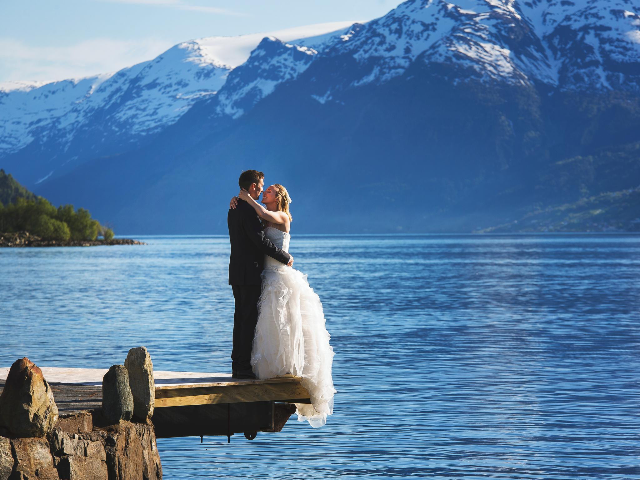A bride and groom out by the fjord with mountains in the background in Ullensvang in Fjord Norway
