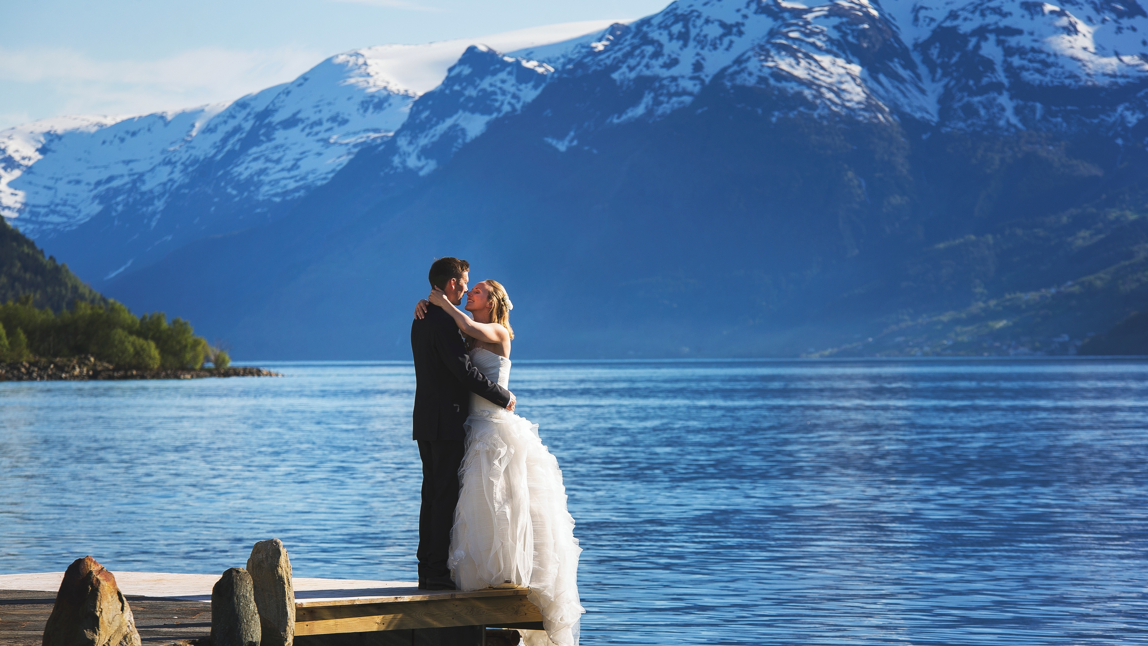 A bride and groom out by the fjord with mountains in the background in Ullensvang in Fjord Norway