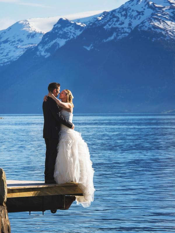A bride and groom out by the fjord with mountains in the background in Ullensvang in Fjord Norway