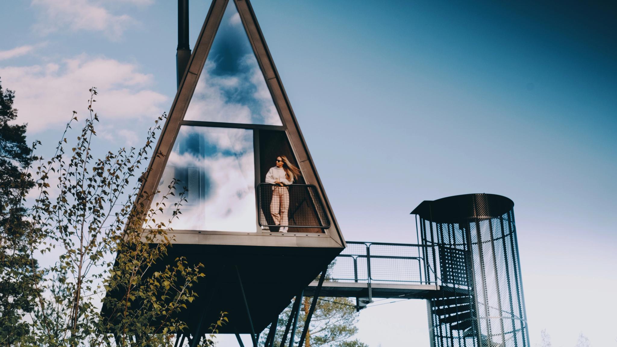 A woman is enjoying the view from one of the treehouses at PAN treetop cabins in Finnskogen, Eastern Norway