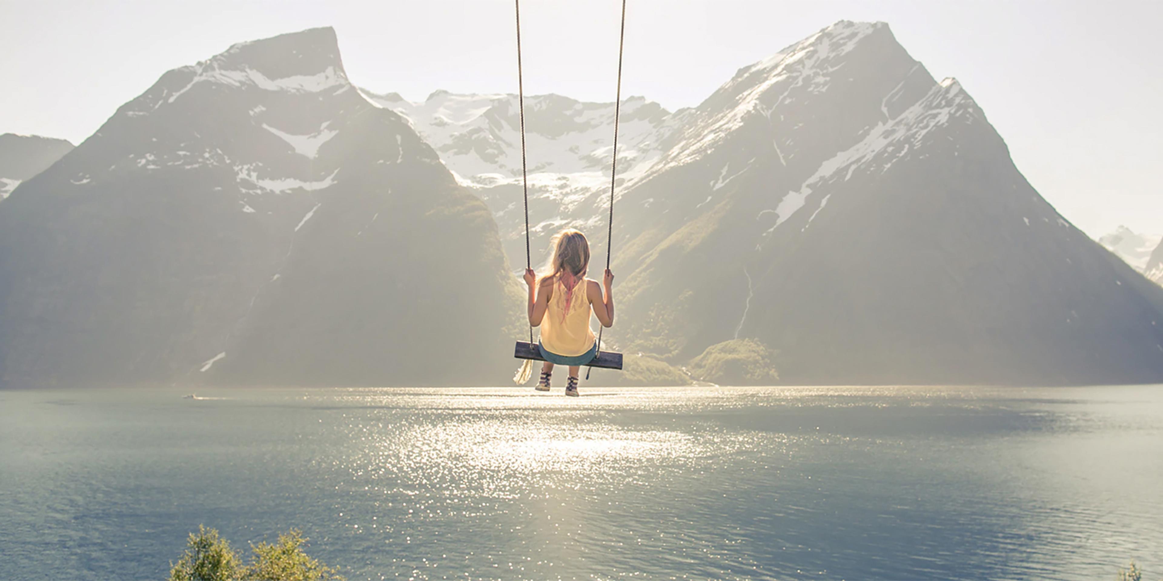 A girl on a the world’s most beautiful swing in Trandal by the Hjørundfjord in Fjord Norway