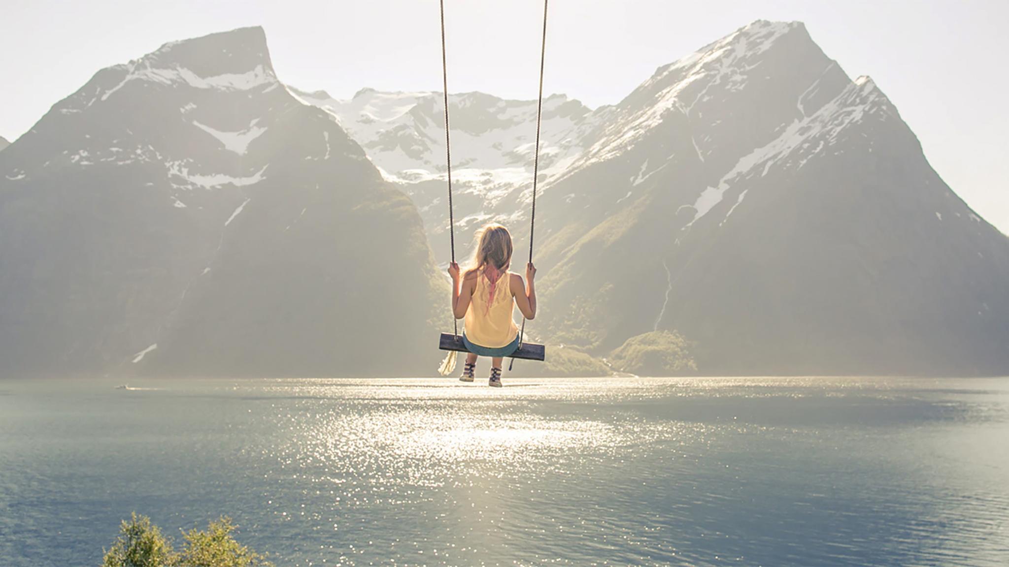A girl on a the world’s most beautiful swing in Trandal by the Hjørundfjord in Fjord Norway