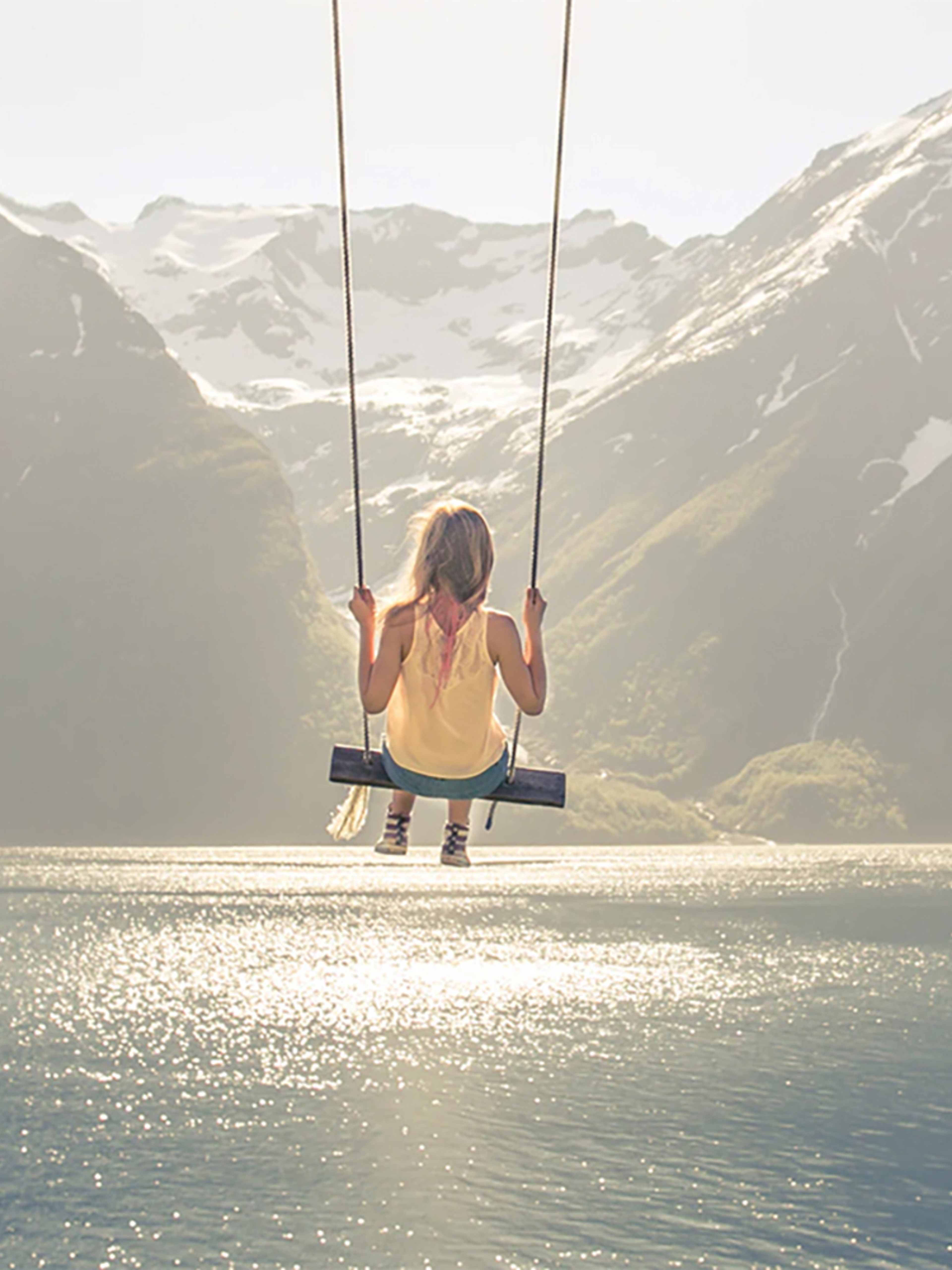 A girl on a the world’s most beautiful swing in Trandal by the Hjørundfjord in Fjord Norway