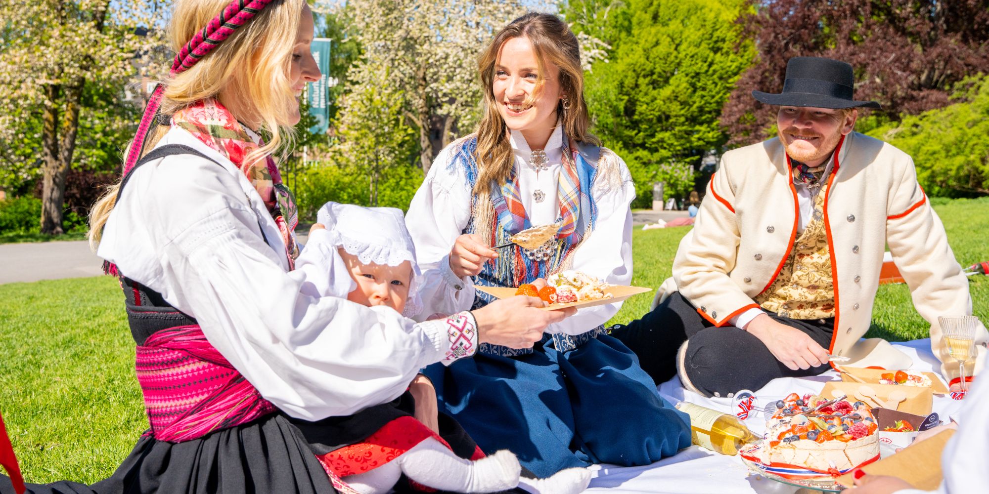 People enjoying festive food in the park wearing bunads on 17 of May - Norway’s national day