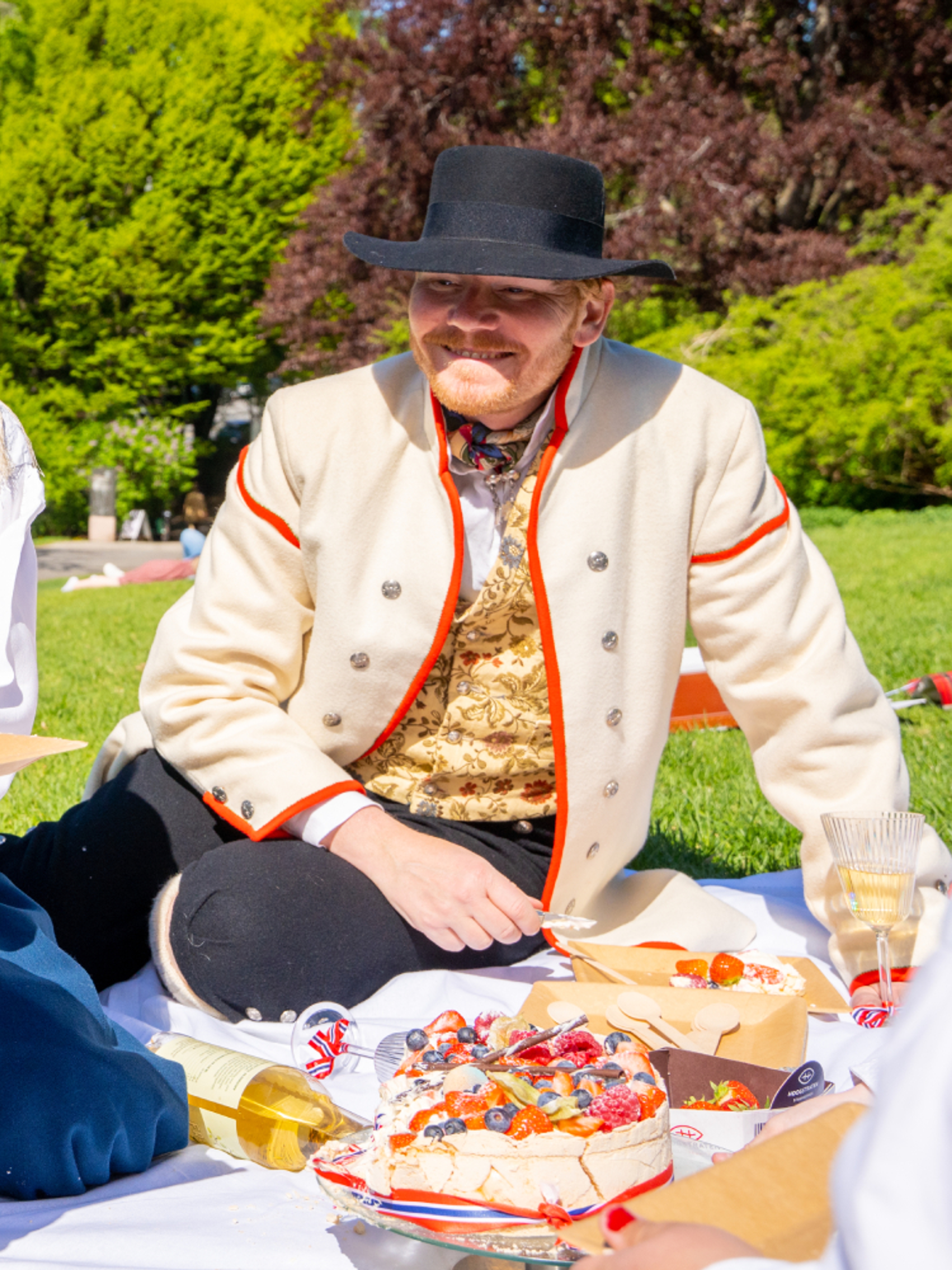 People enjoying festive food in the park wearing bunads on 17 of May - Norway’s national day