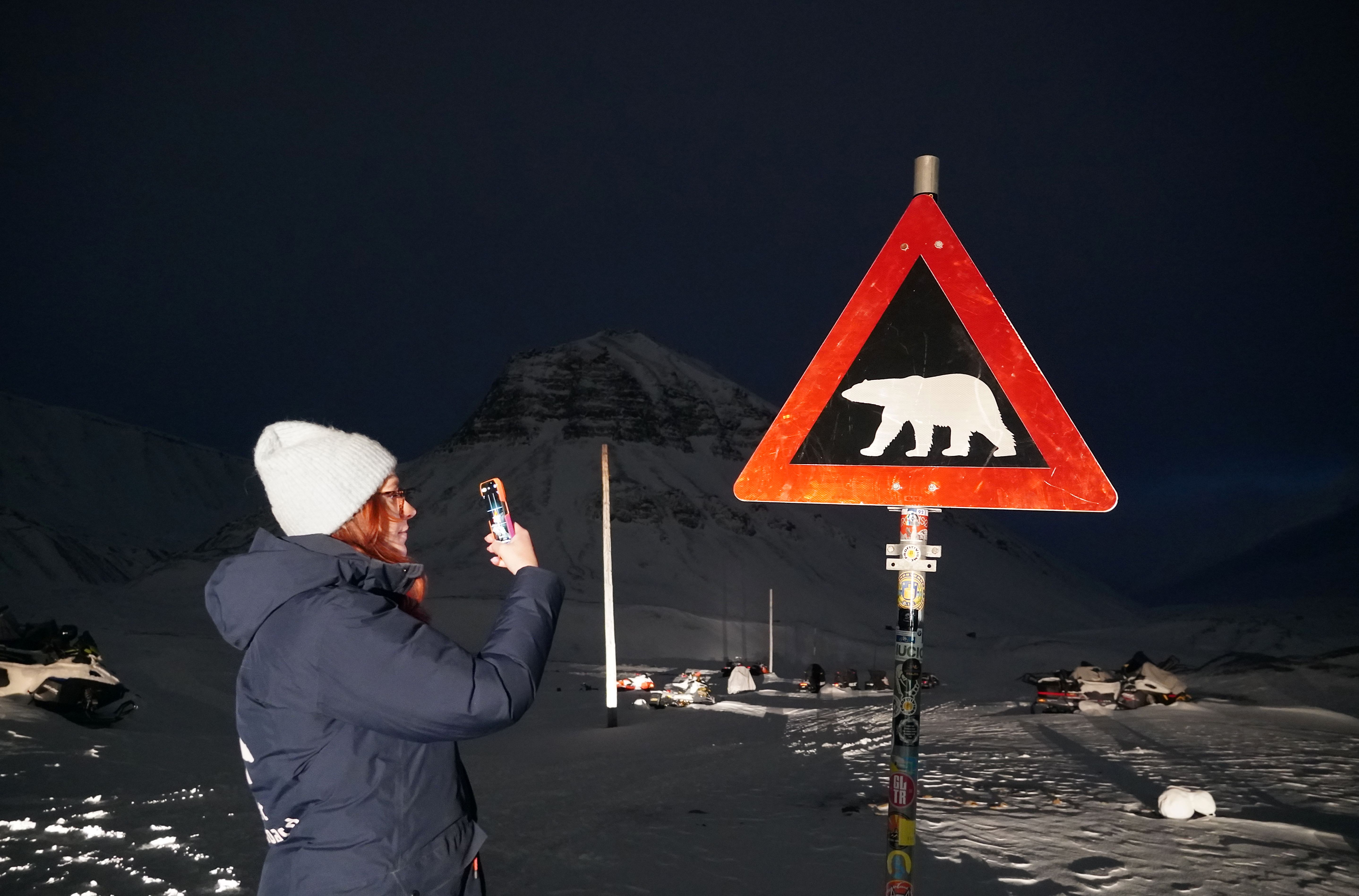 Woman in front of a polar bear sign in Svalbard