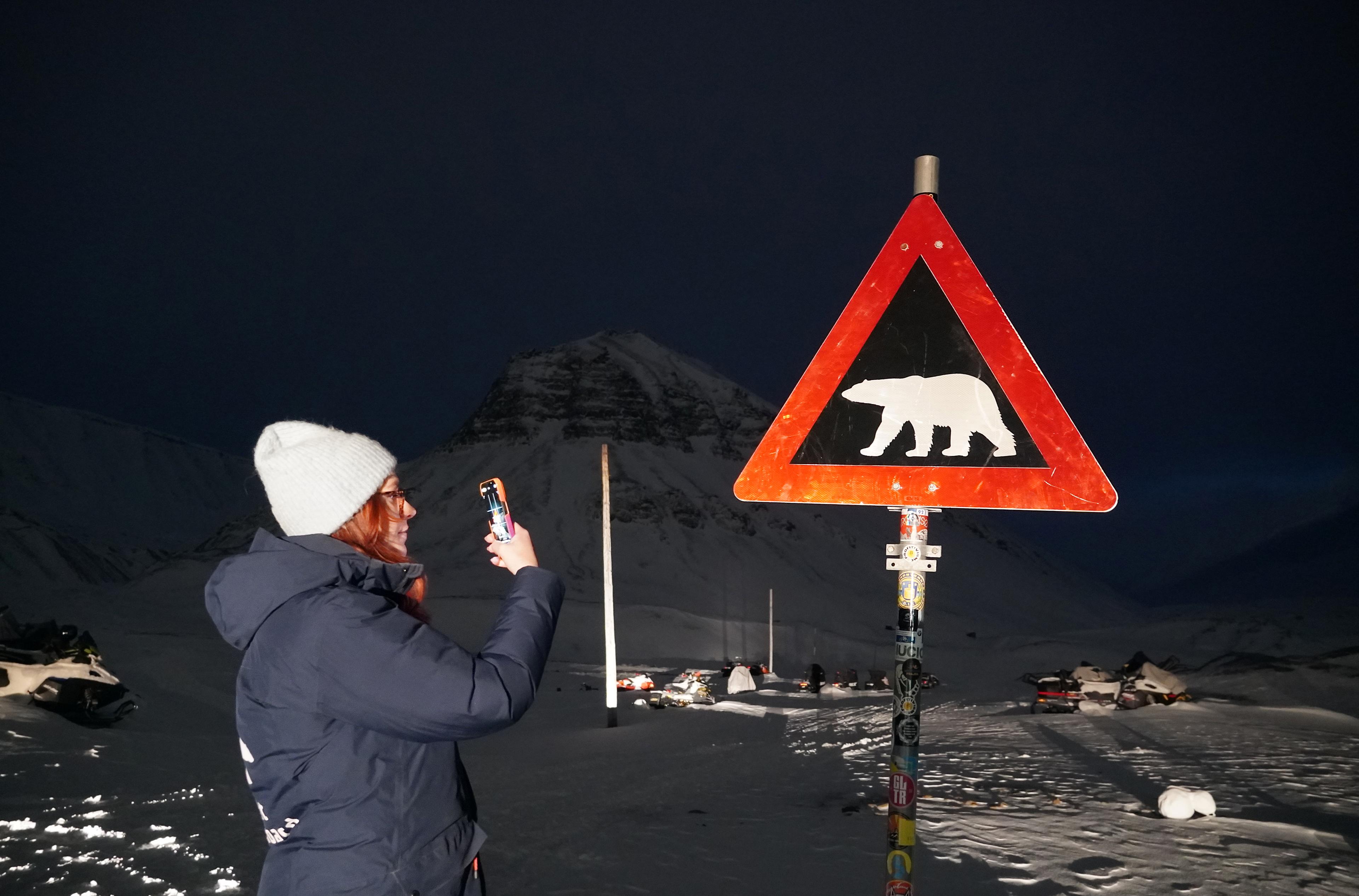 Woman in front of a polar bear sign in Svalbard