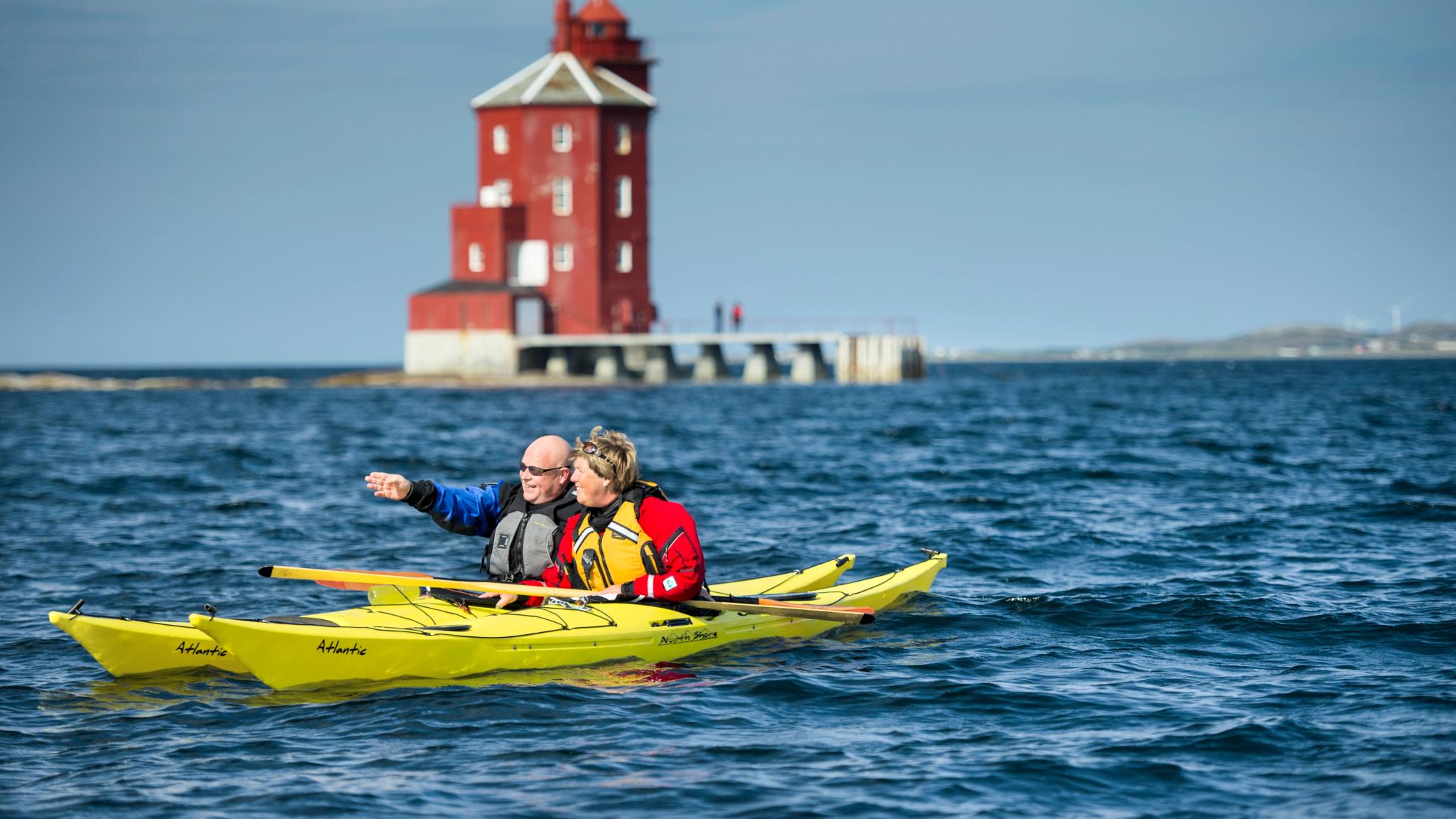 Two people kayaking in front of Kjeungskjær lighthouse in Trøndelag, Norway