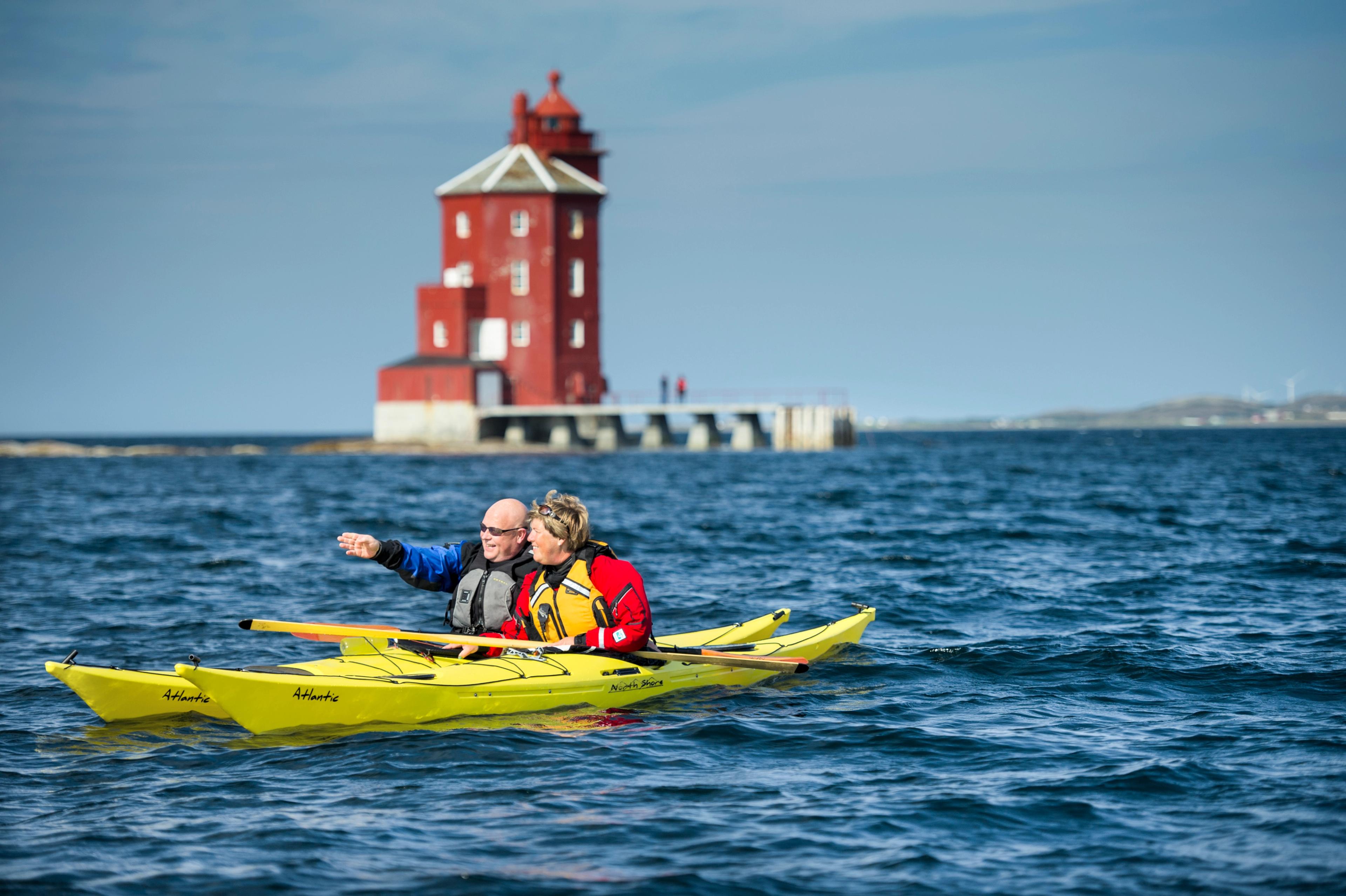 Two people kayaking in front of Kjeungskjær lighthouse in Trøndelag, Norway