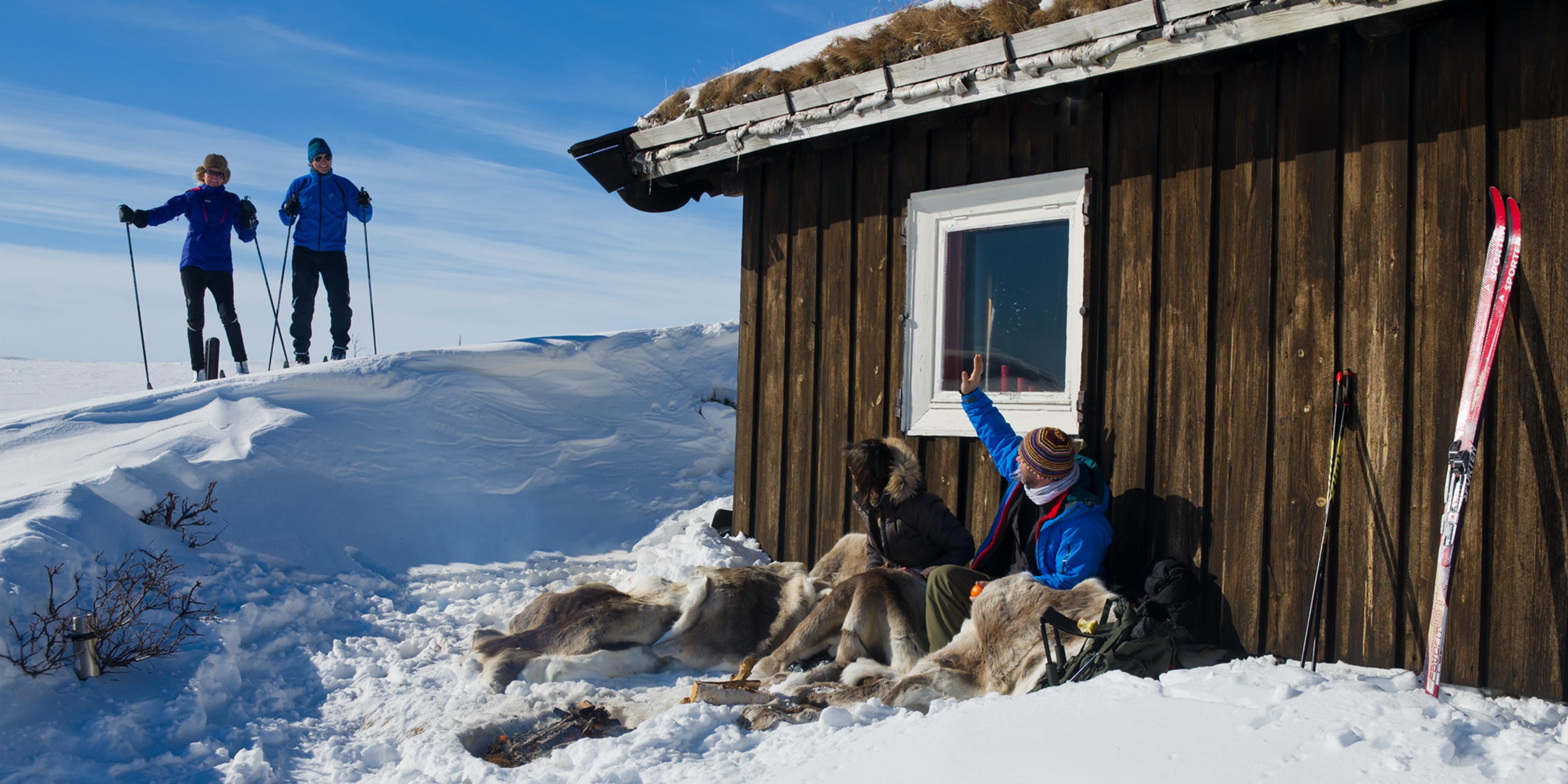 Two couples enjoying the snowy landscape surrounding a cabin in Rauland