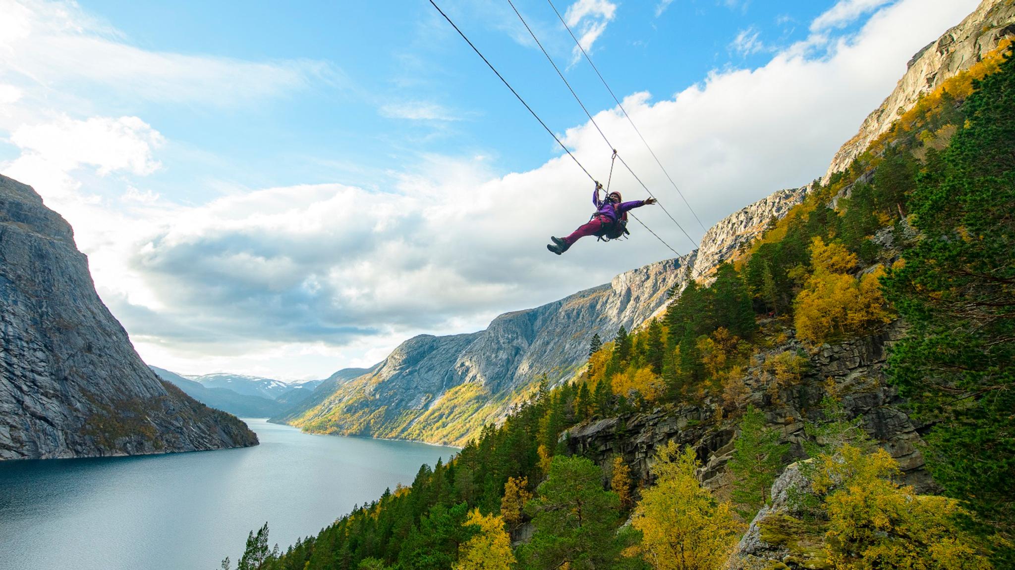 En kvinna som glider ner för en zipline i närheten av Trolltunga i Fjord Norge