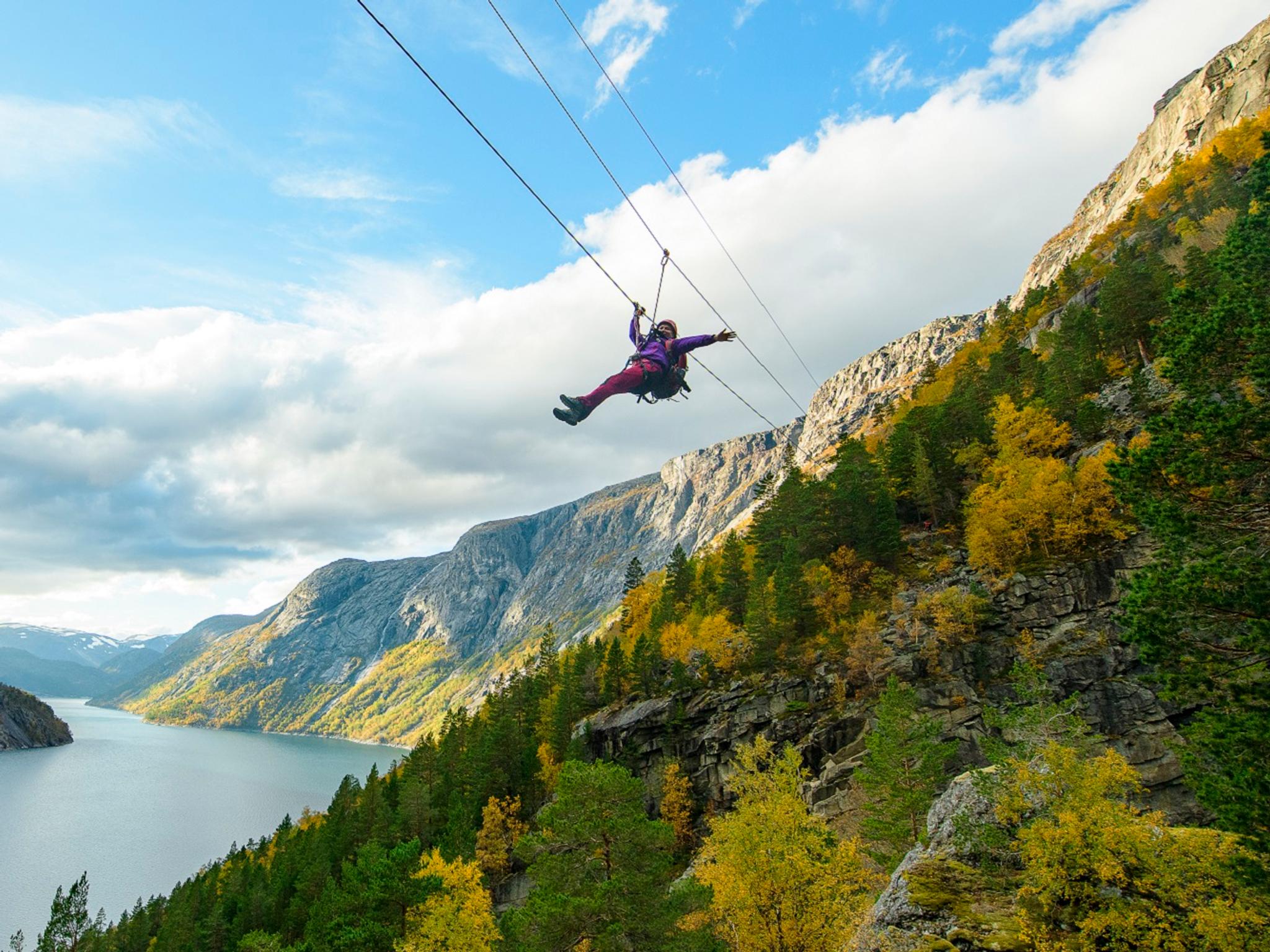 En kvinna som glider ner för en zipline i närheten av Trolltunga i Fjord Norge
