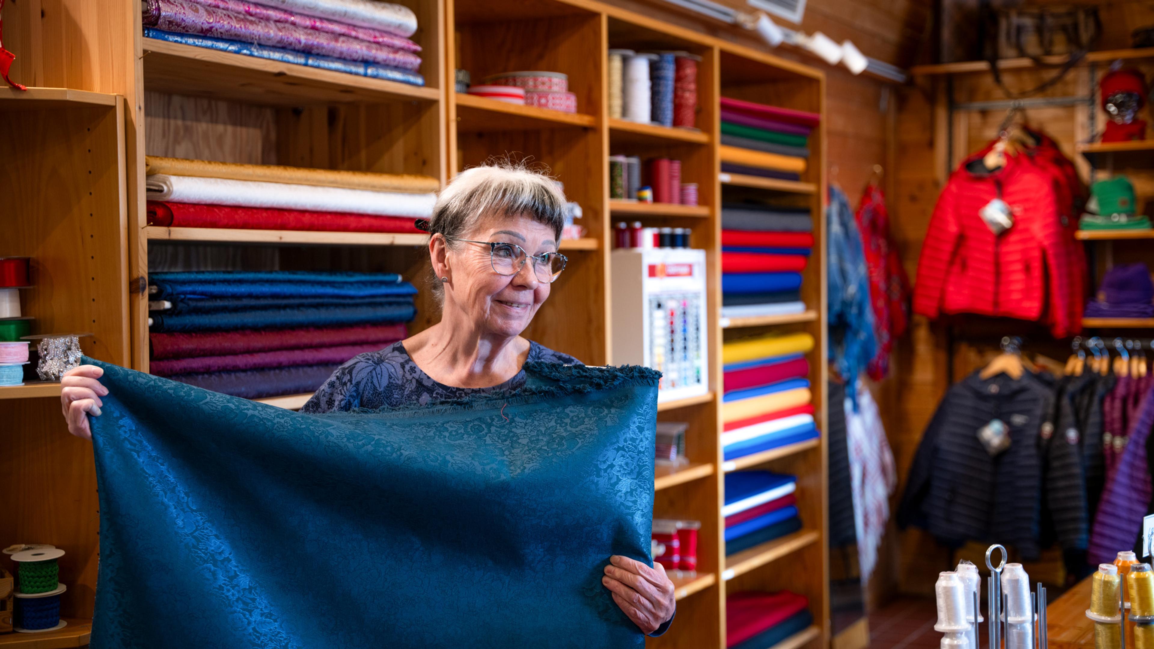 Kirsti Gulsrud showing off fabrics that are for sale at Sapmi Park in Karasjok