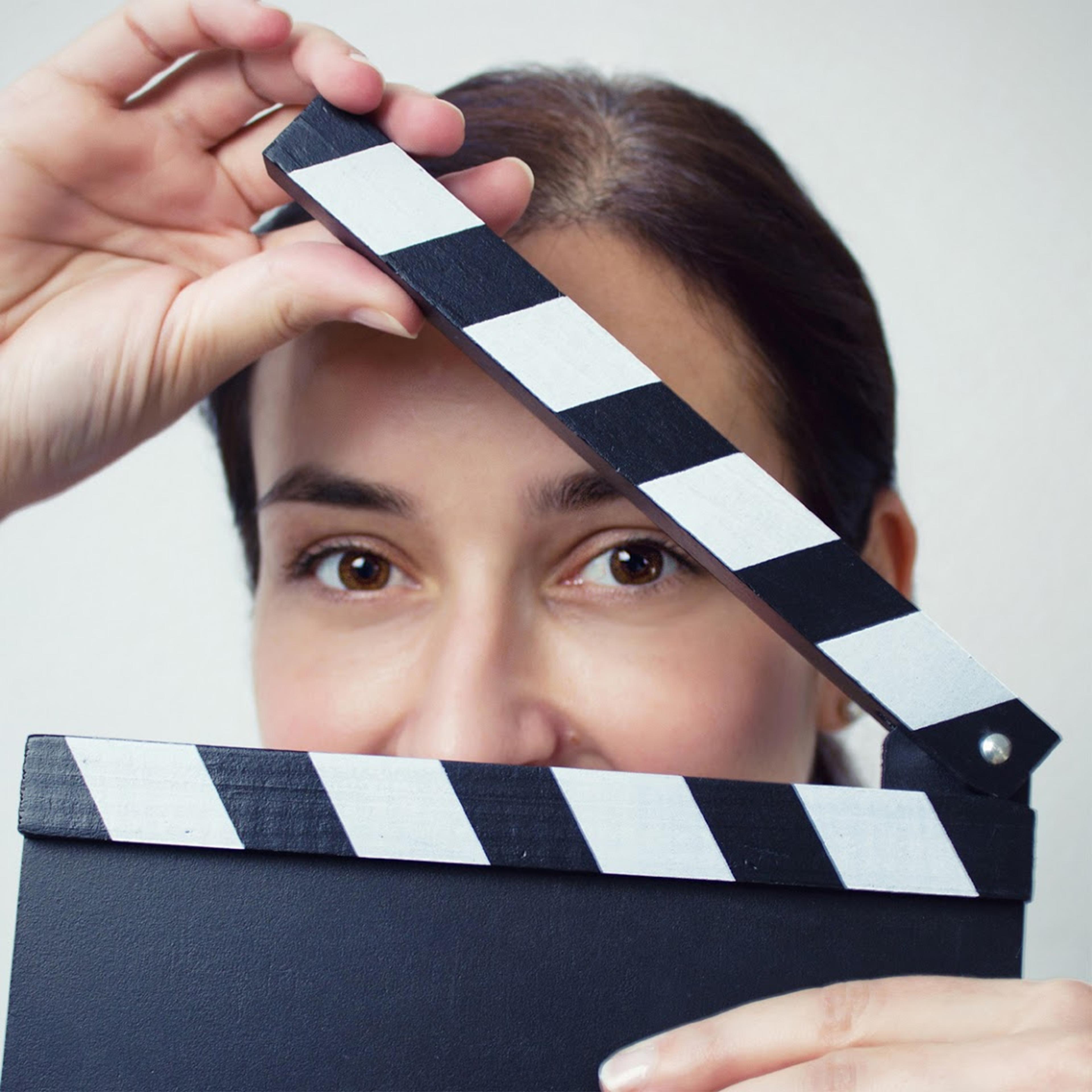 A portrait of Andrea David behind a clapperboard